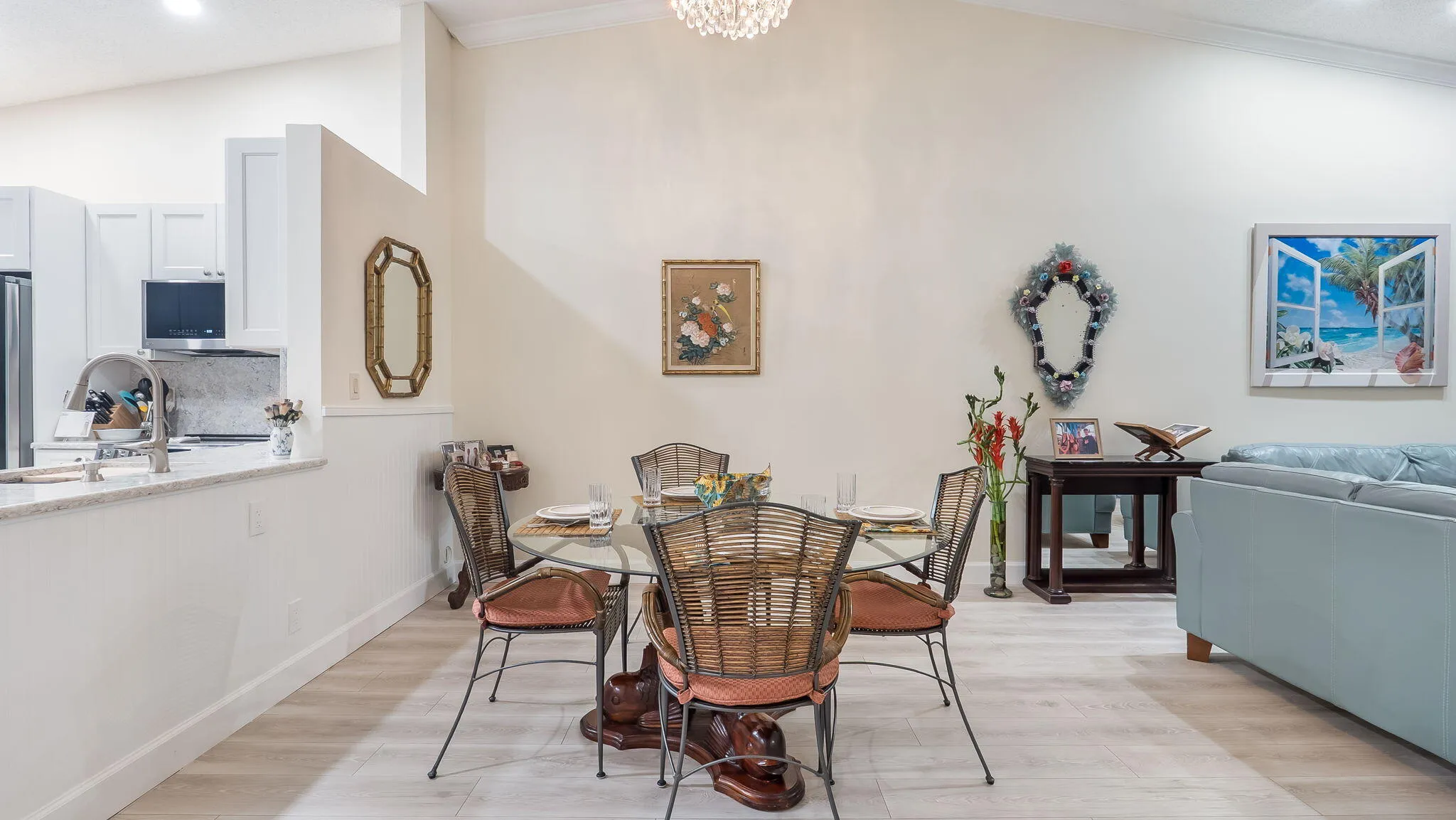Open-concept living area with vaulted ceilings, wood-finish flooring, and a kitchen pass-through featuring stone countertops and white cabinetry