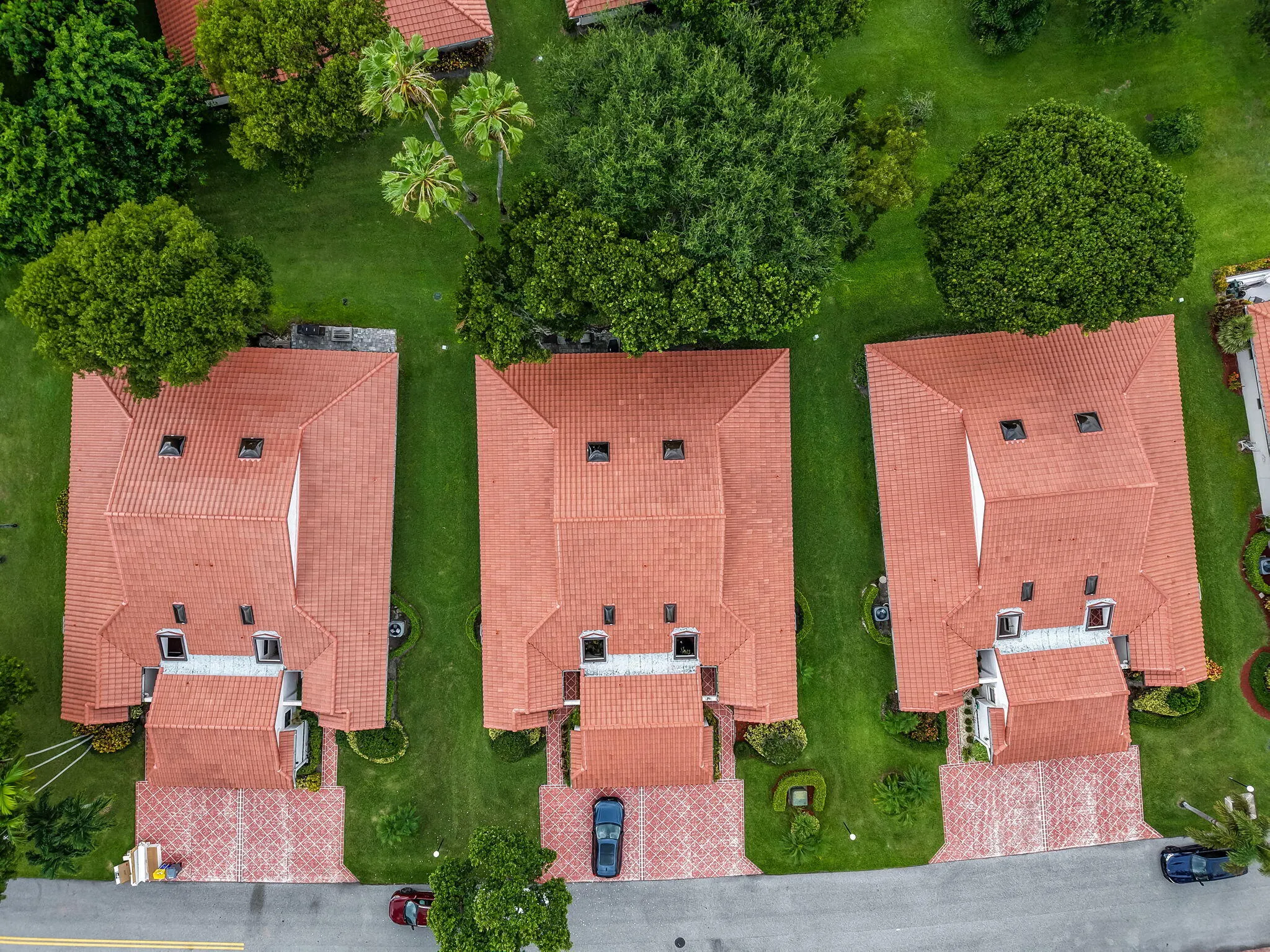 Three residences featuring red tile roofs and paver driveways