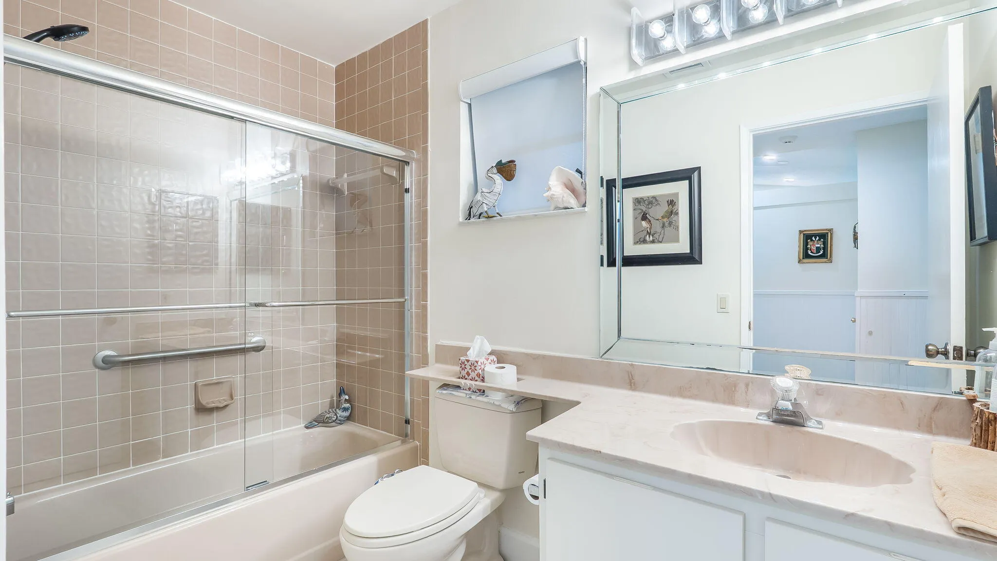 Bathroom featuring a combination tub/shower with sliding glass doors, a vanity with an integrated sink and countertop, and a large wall-mounted mirror