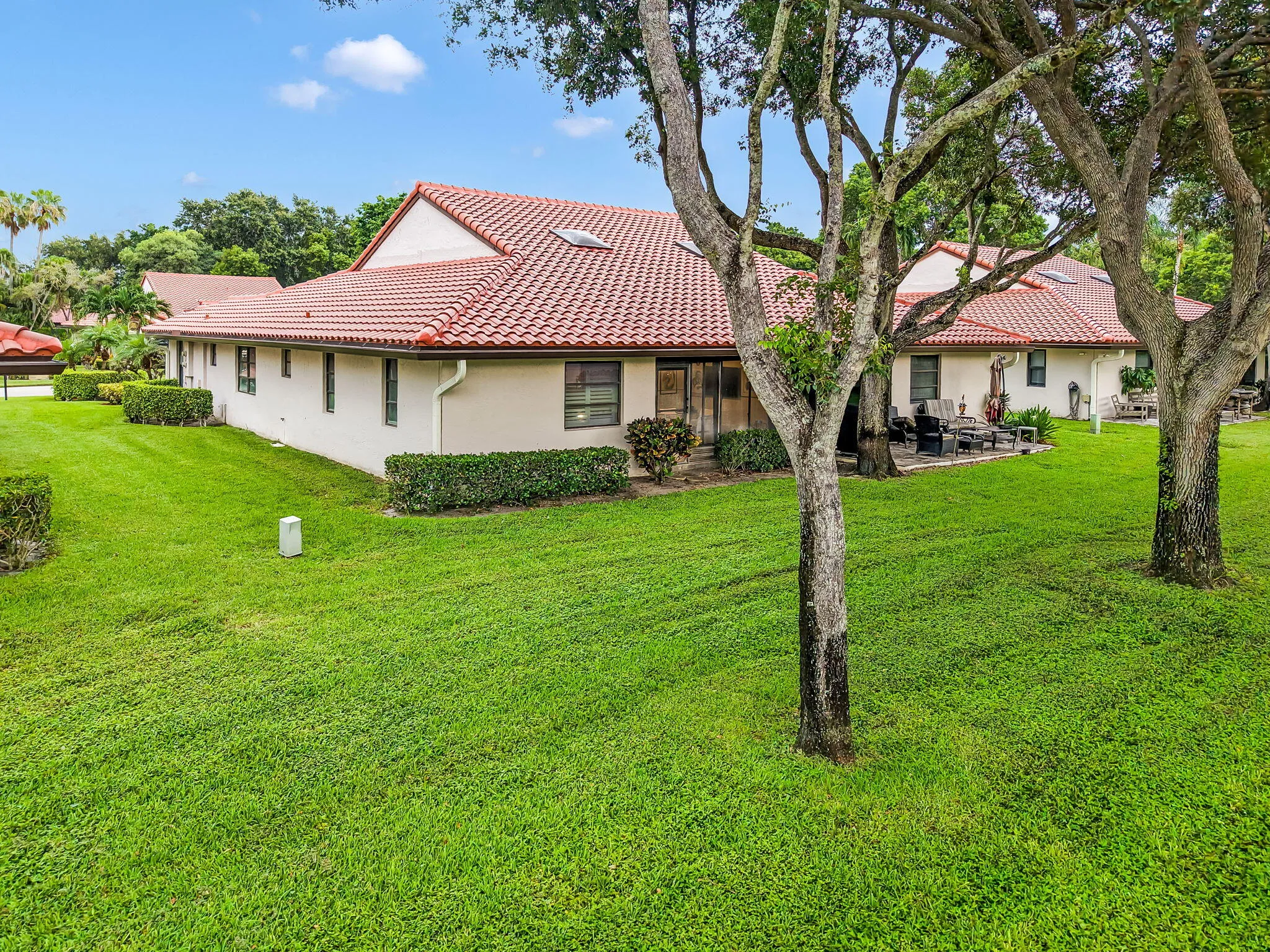Expansive green lawn bordering a residence with a red tile roof and light-colored stucco exterior