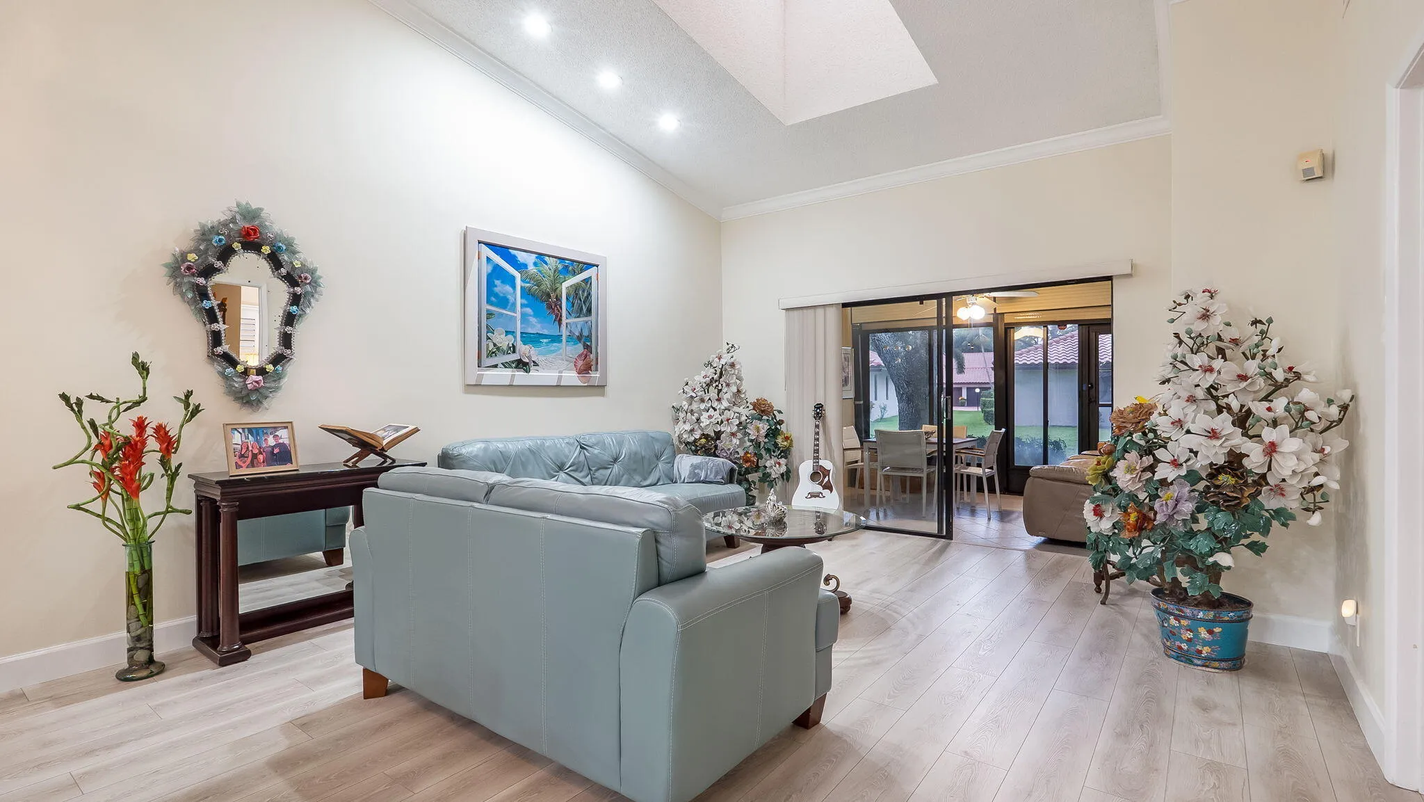 Spacious living area featuring vaulted ceilings with recessed lighting, light wood-finish flooring, and crown molding