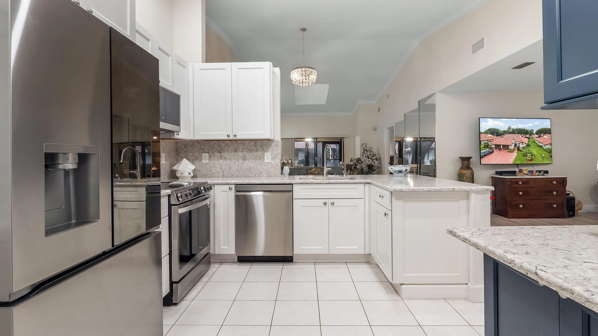 Kitchen featuring white cabinetry, light-toned countertops, stainless steel appliances, and white tile flooring