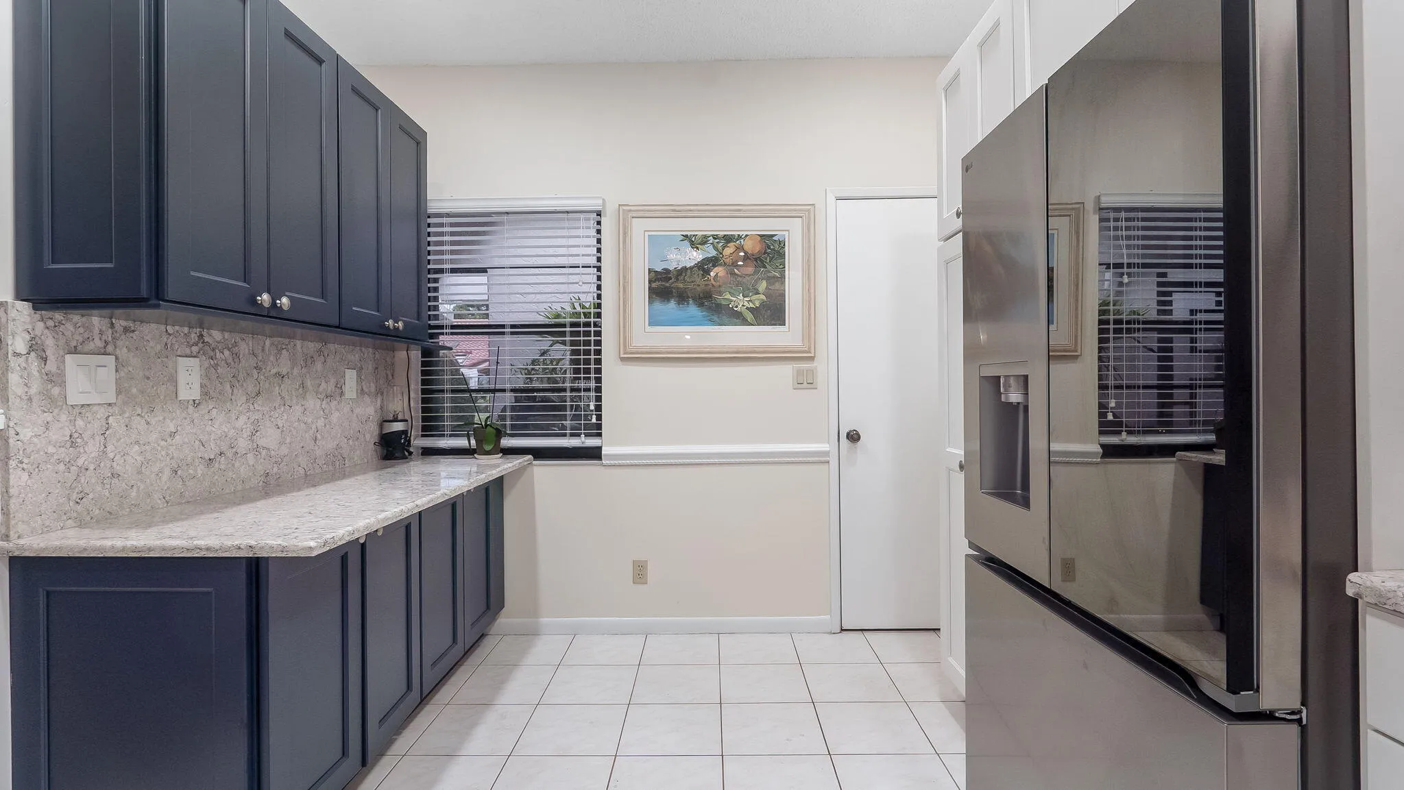 Kitchen featuring dark blue cabinetry, light-toned countertops, a matching backsplash, and tile flooring