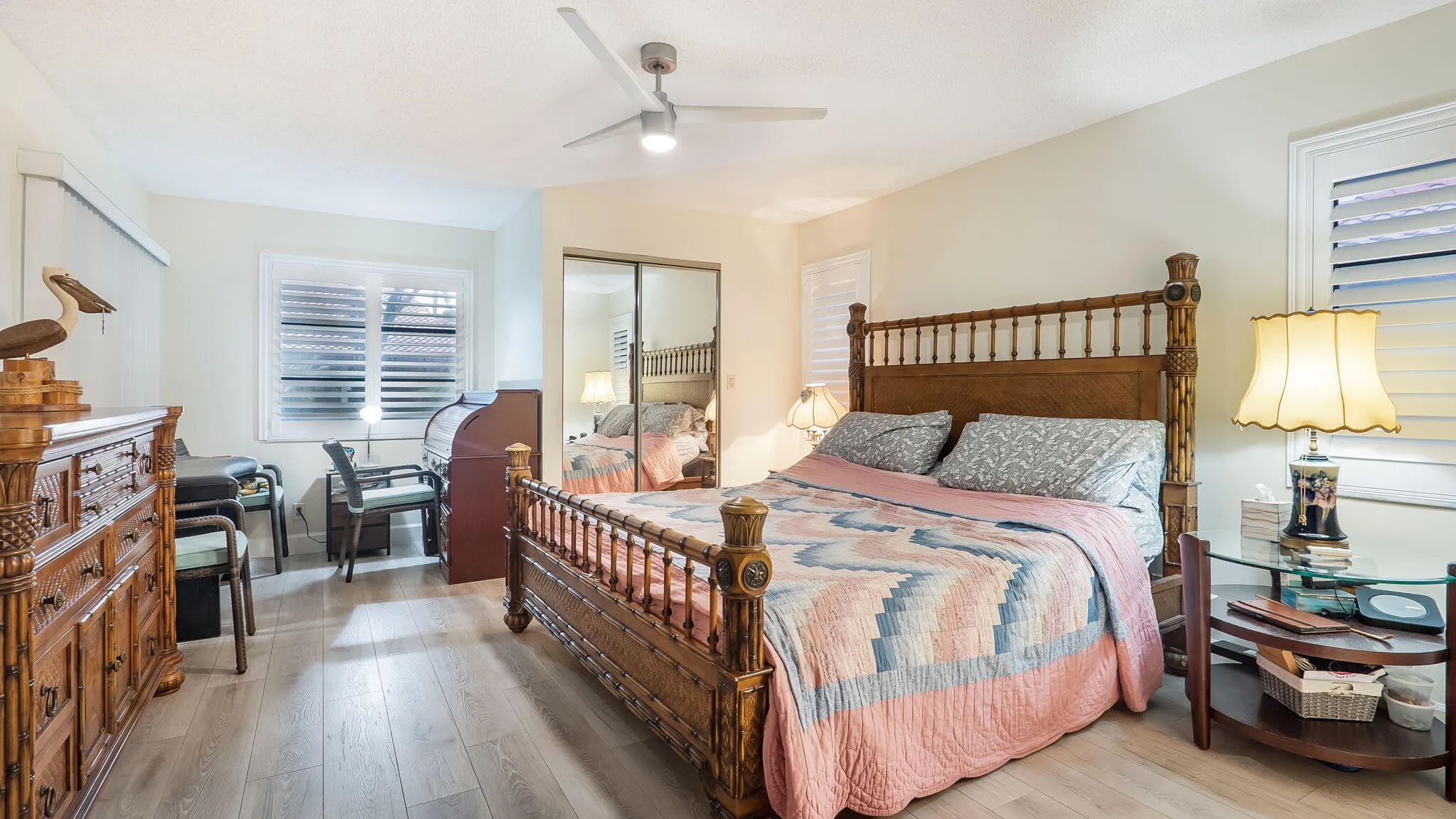 Light wood-finish flooring with white walls and plantation shutters