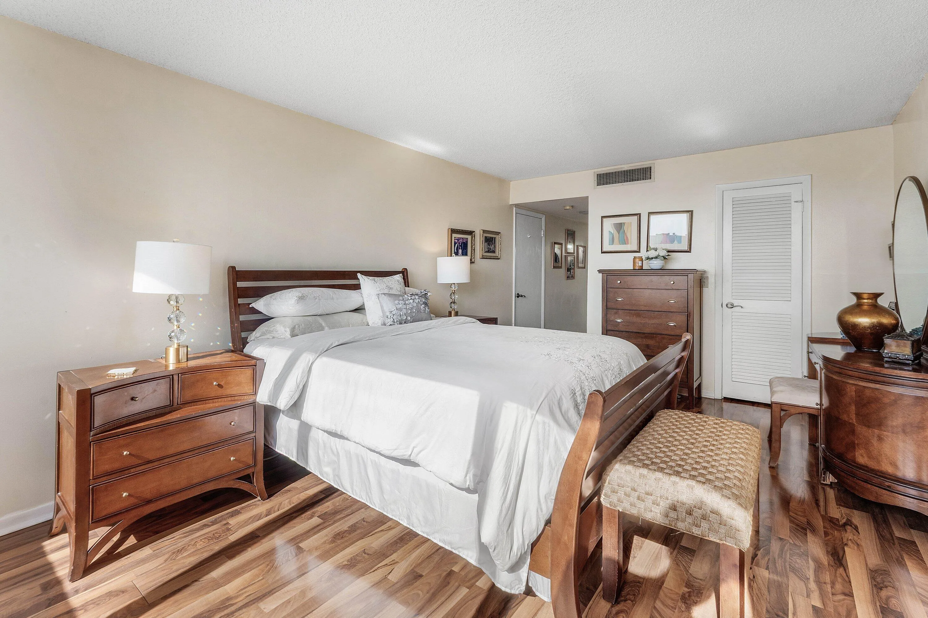 Bedroom featuring warm-toned wood-finish flooring, neutral wall paint, and a white louvered door