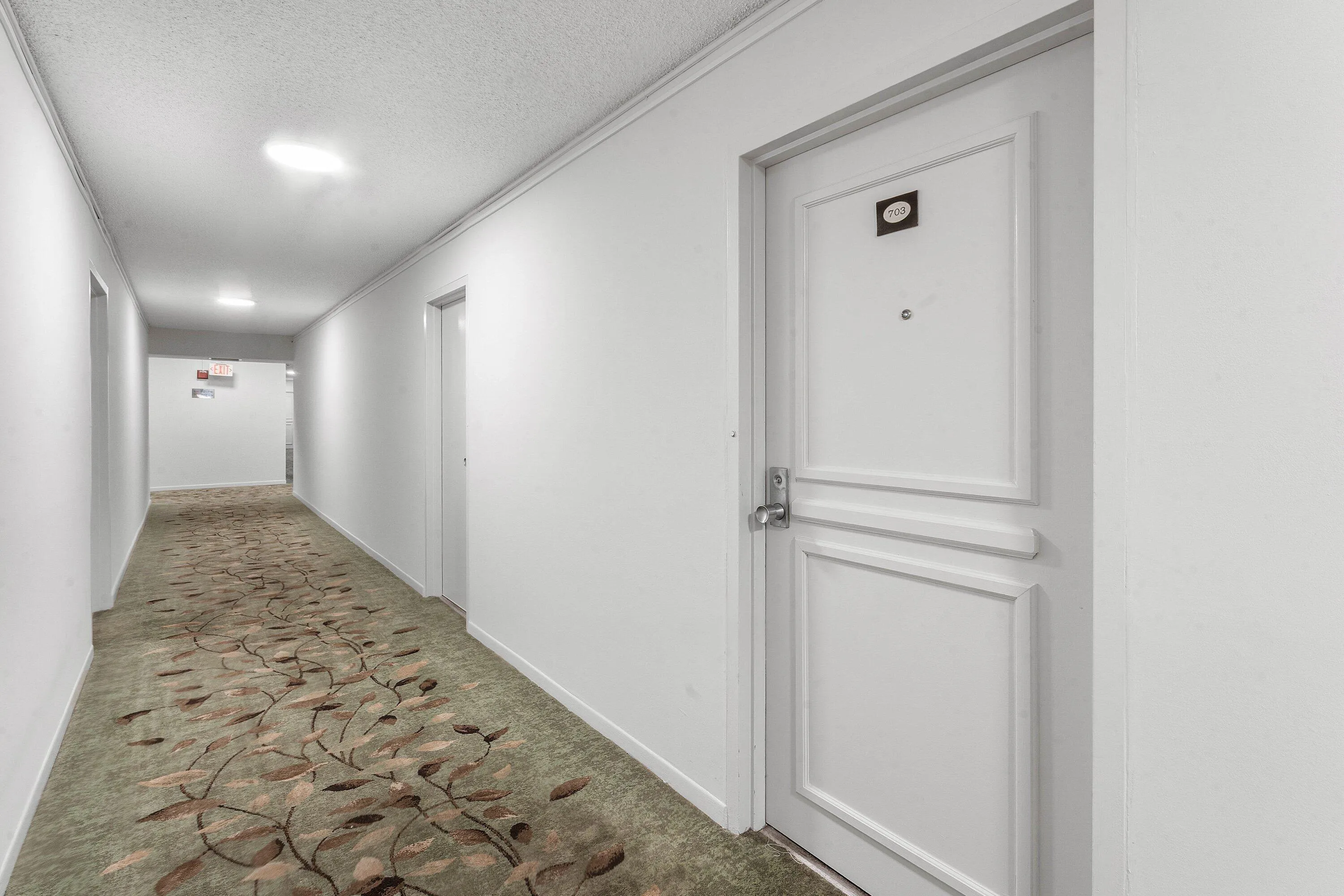 Corridor featuring a patterned carpet runner, white walls, and recessed lighting