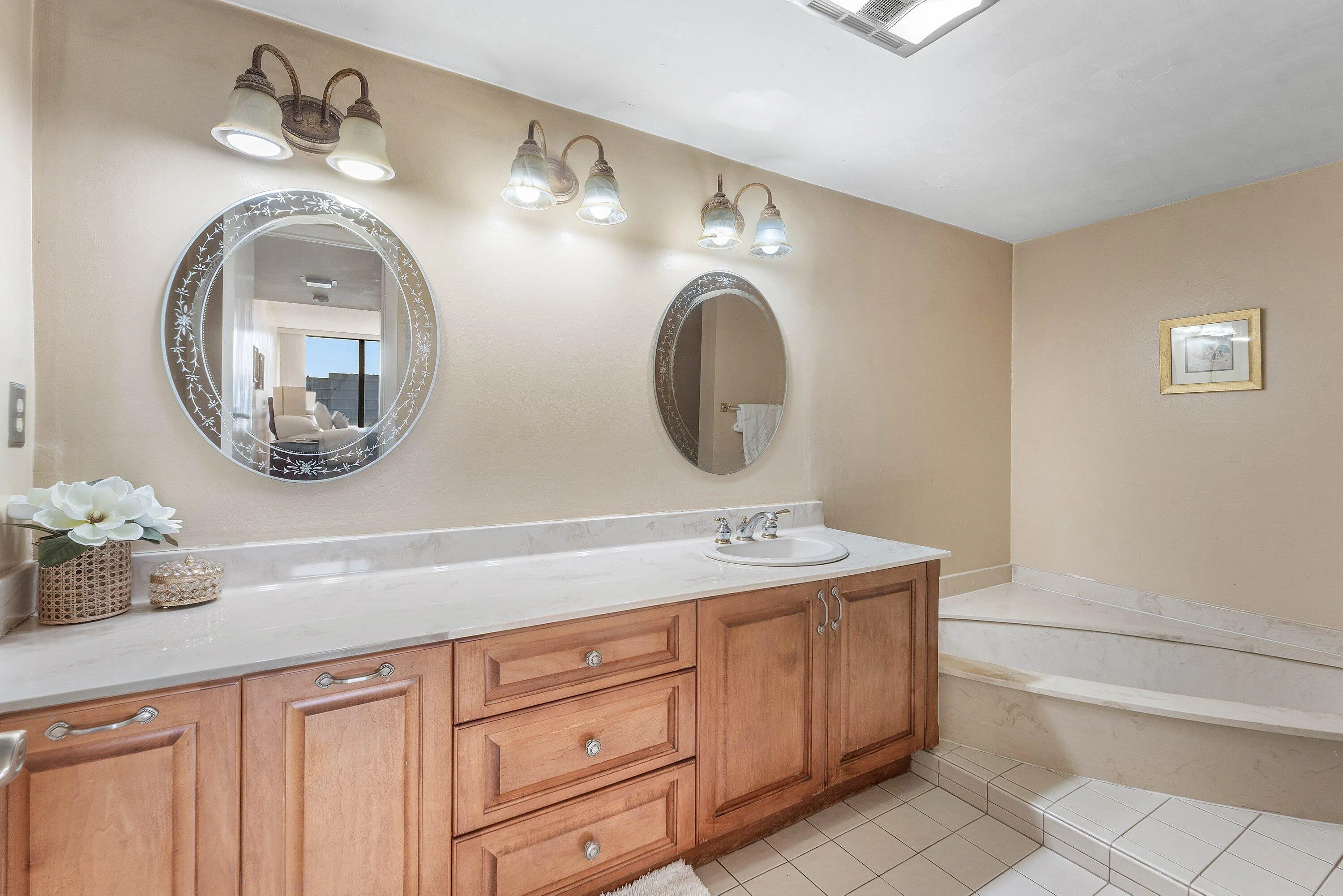 Dual vanities featuring round mirrors, custom wood cabinetry, and a light-toned countertop