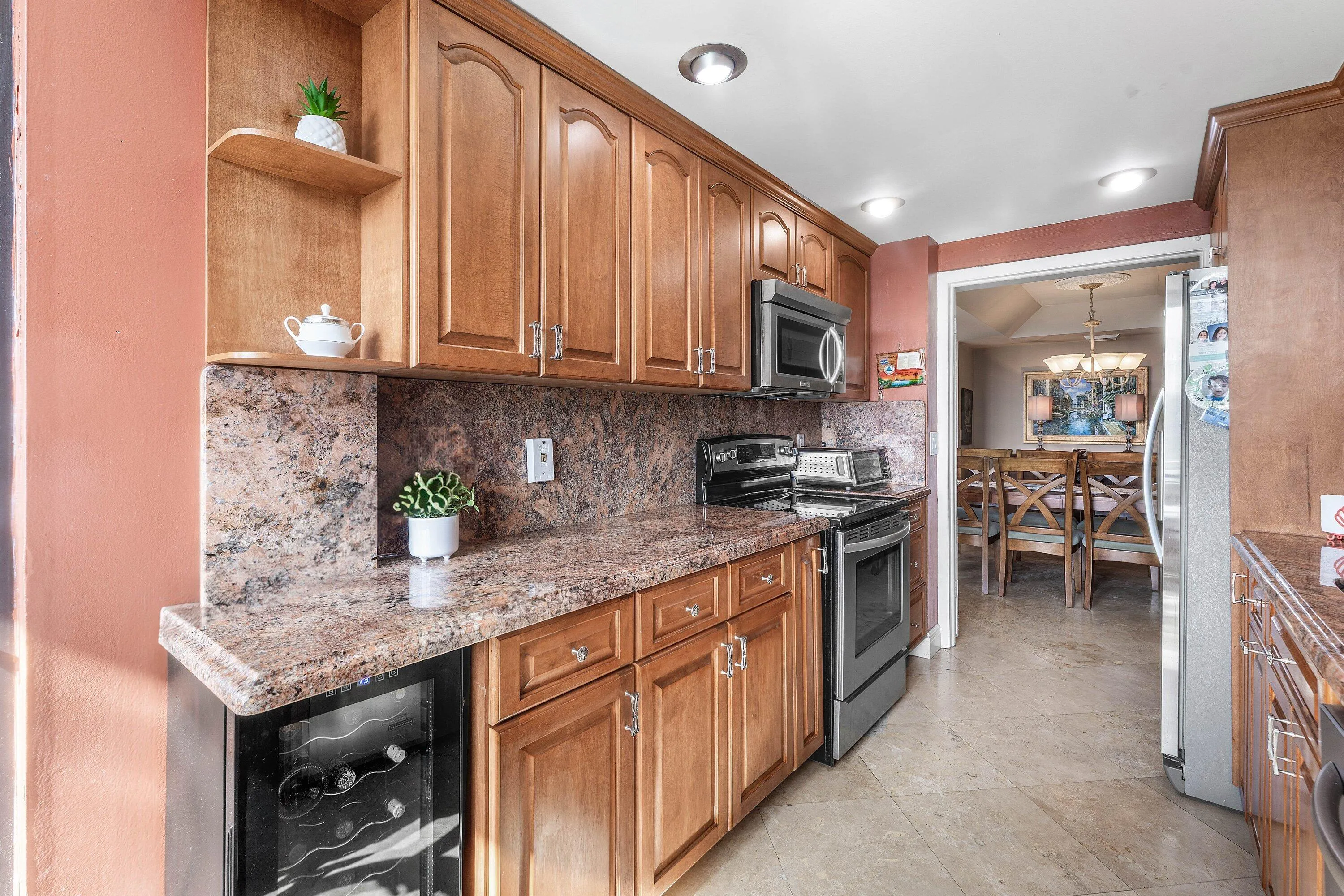 Kitchen featuring wood cabinetry, granite countertops with matching backsplash, and stainless steel appliances