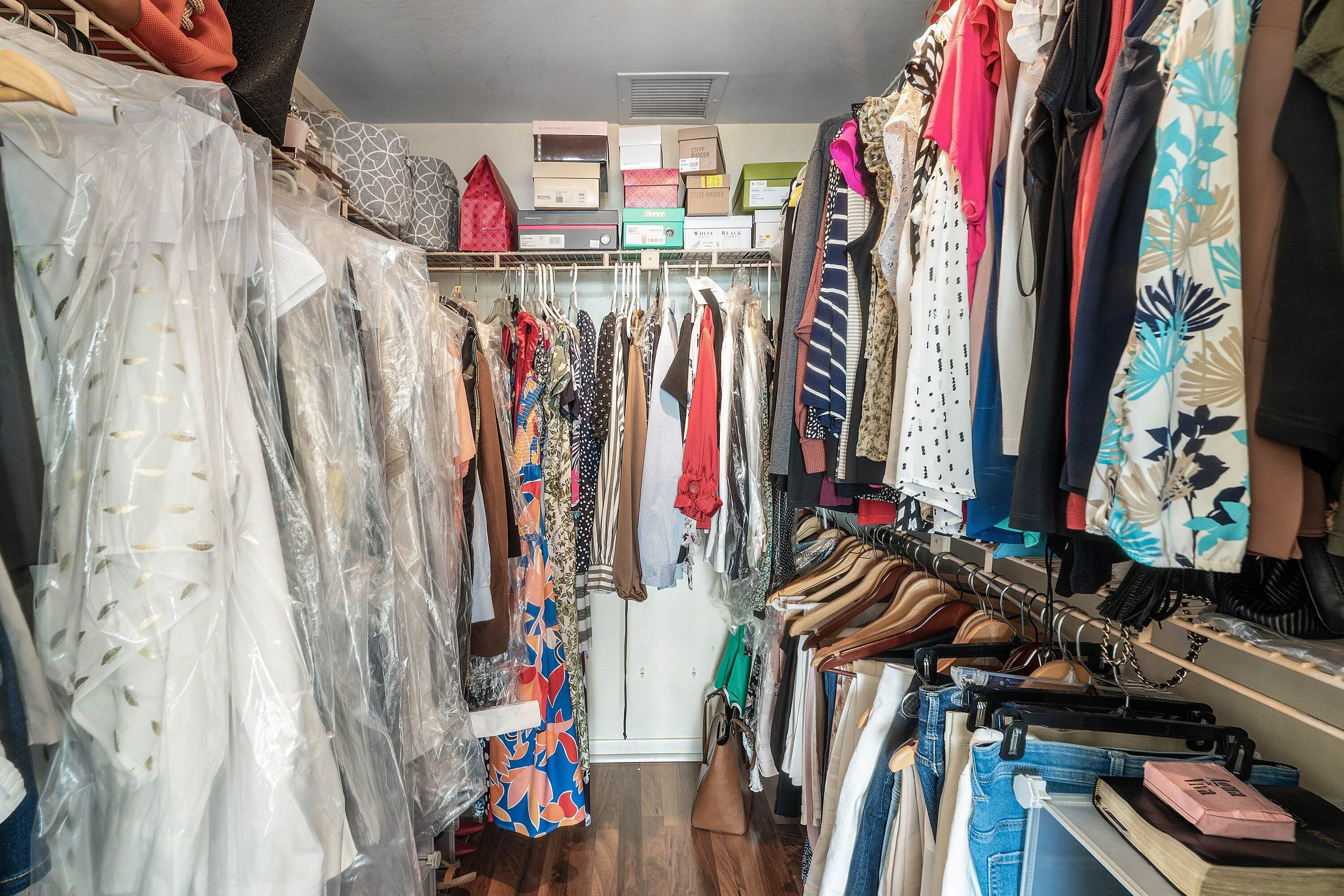 Walk-in closet featuring wood-finish flooring, ample hanging rods, and integrated shelving for organized storage