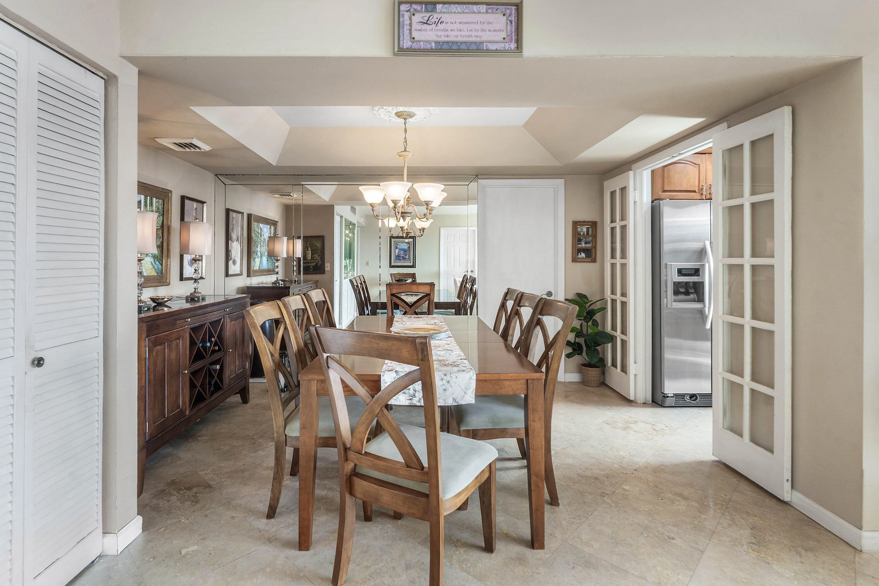Spacious dining area featuring neutral wall paint, tile flooring, a tray ceiling, and French doors