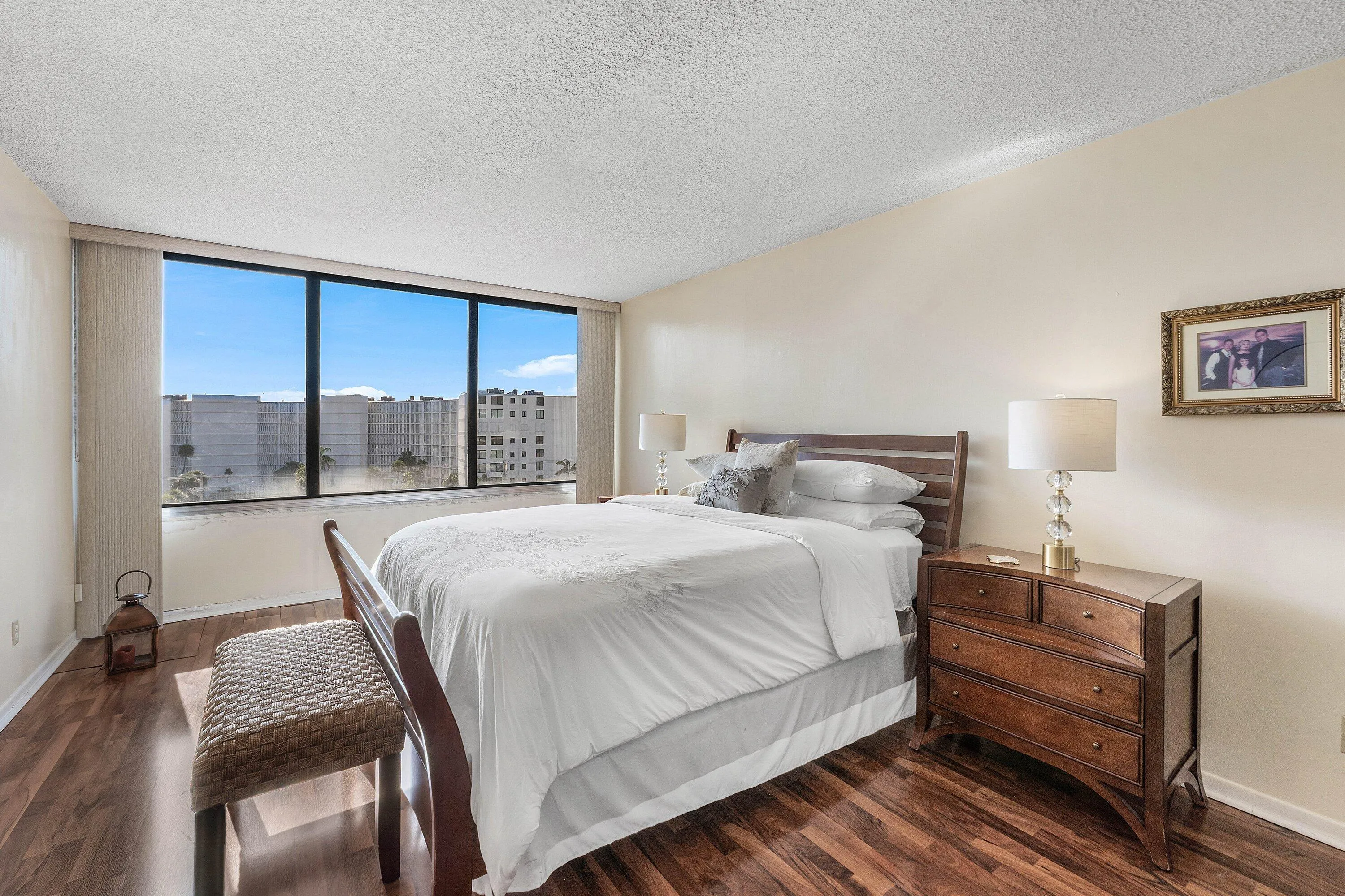 Expansive window wall with a broad urban vista, complemented by dark wood-finish flooring and light-toned walls