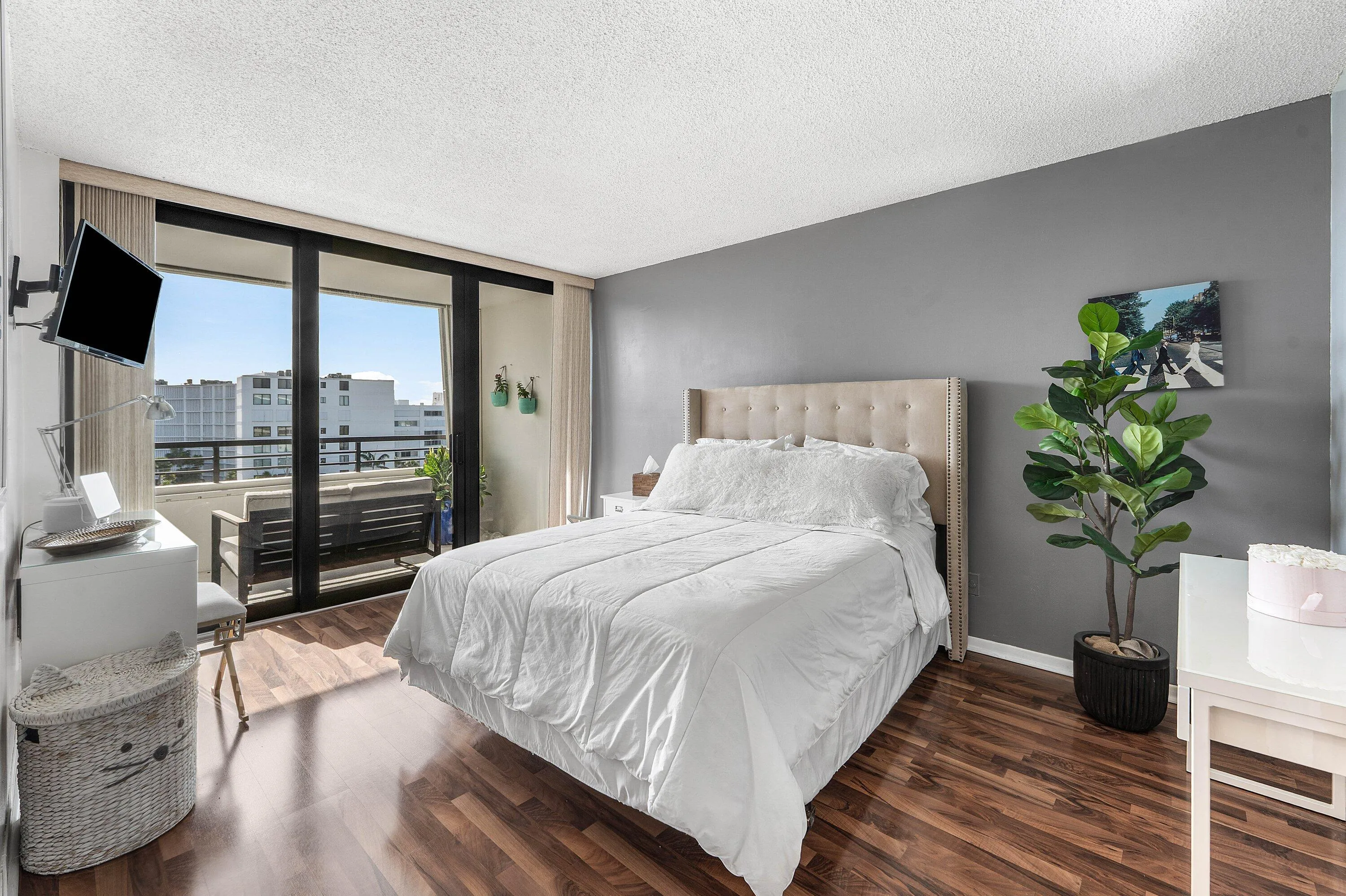 Spacious bedroom featuring wood-finish flooring and direct balcony access through large impact sliding glass doors