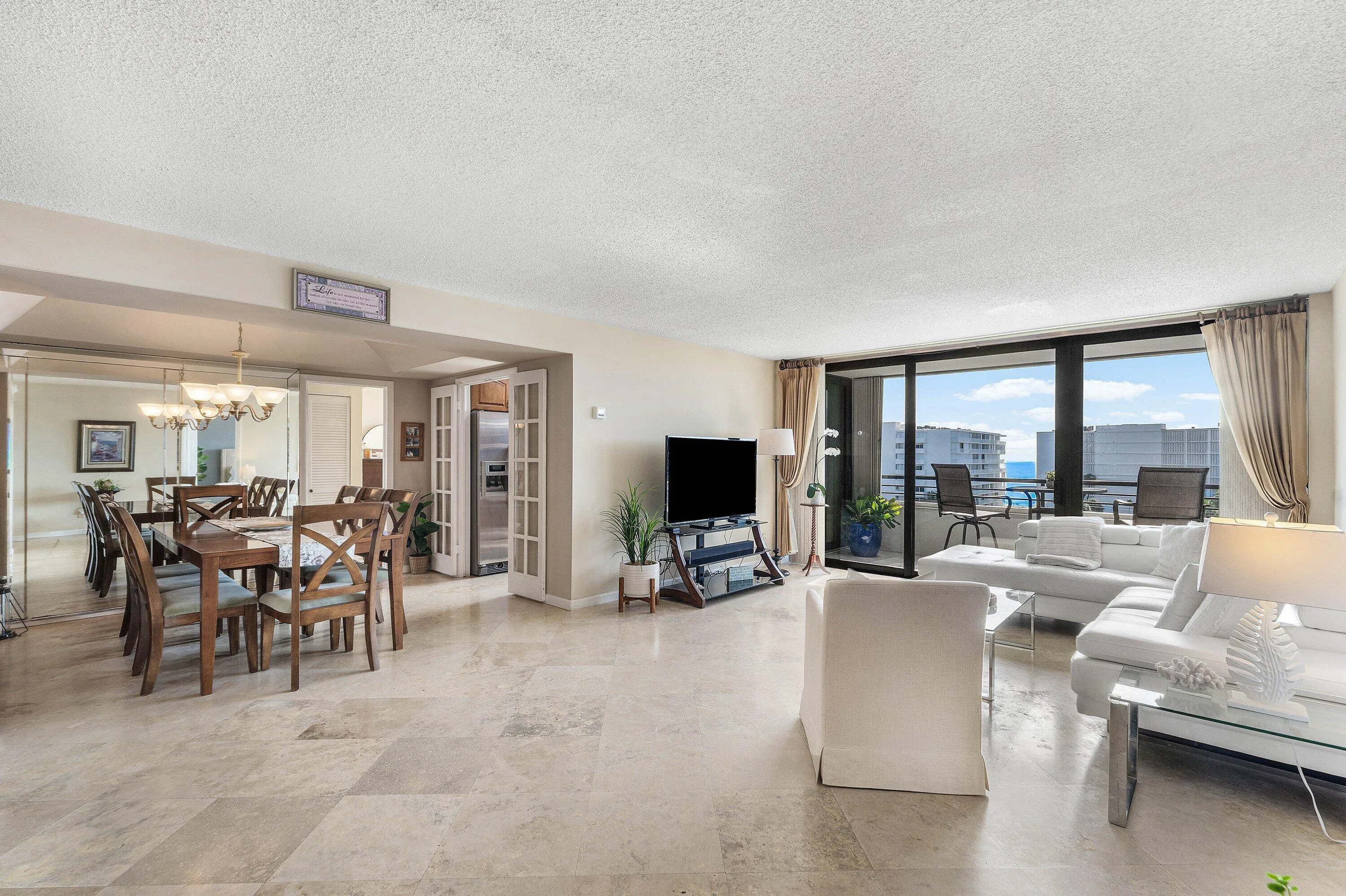 Expansive living area with large format tile flooring and a mirrored dining space