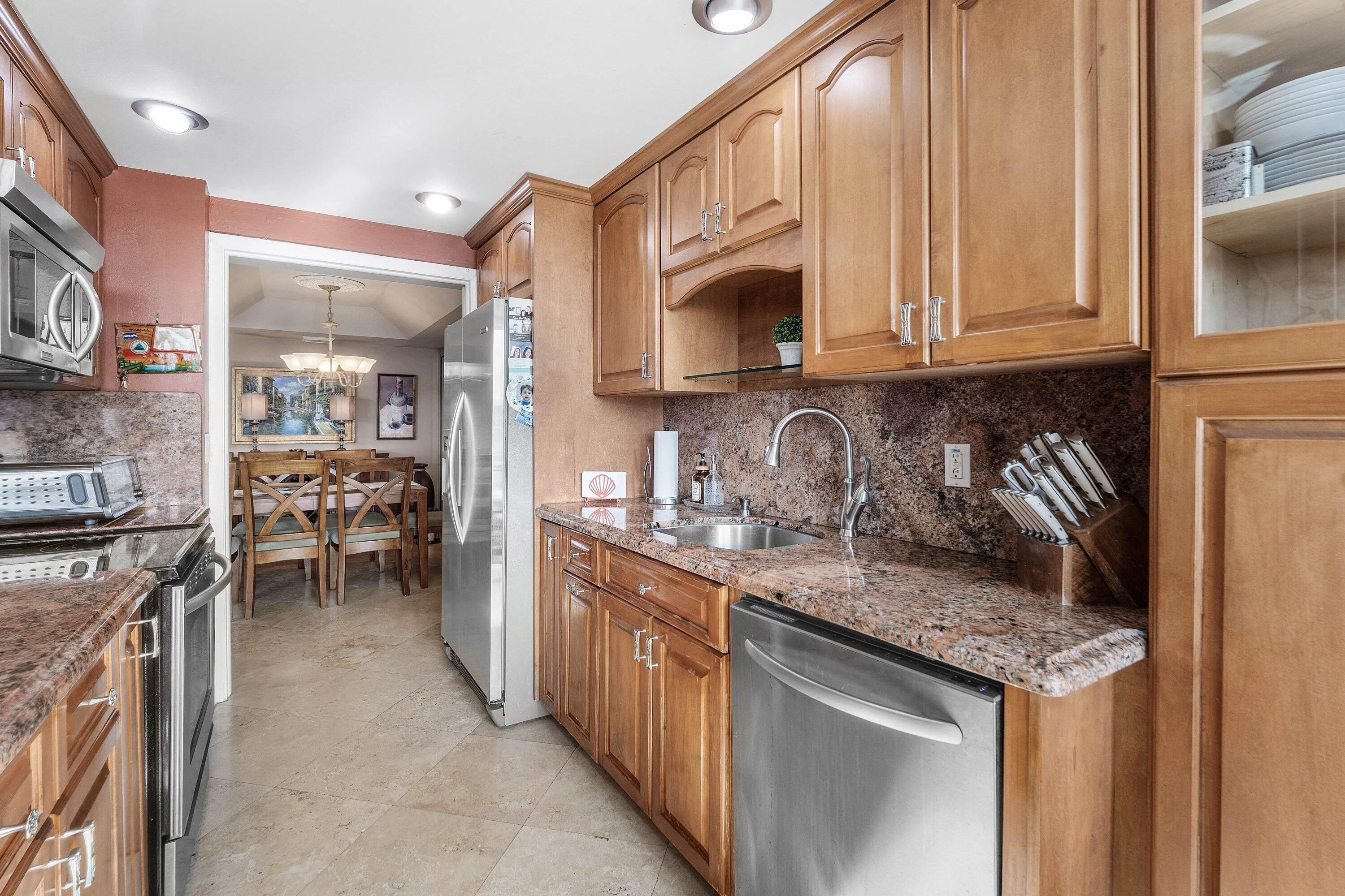 Kitchen featuring wood-finish cabinetry, granite countertops, and stainless steel appliances including a refrigerator, dishwasher, oven, and microwave