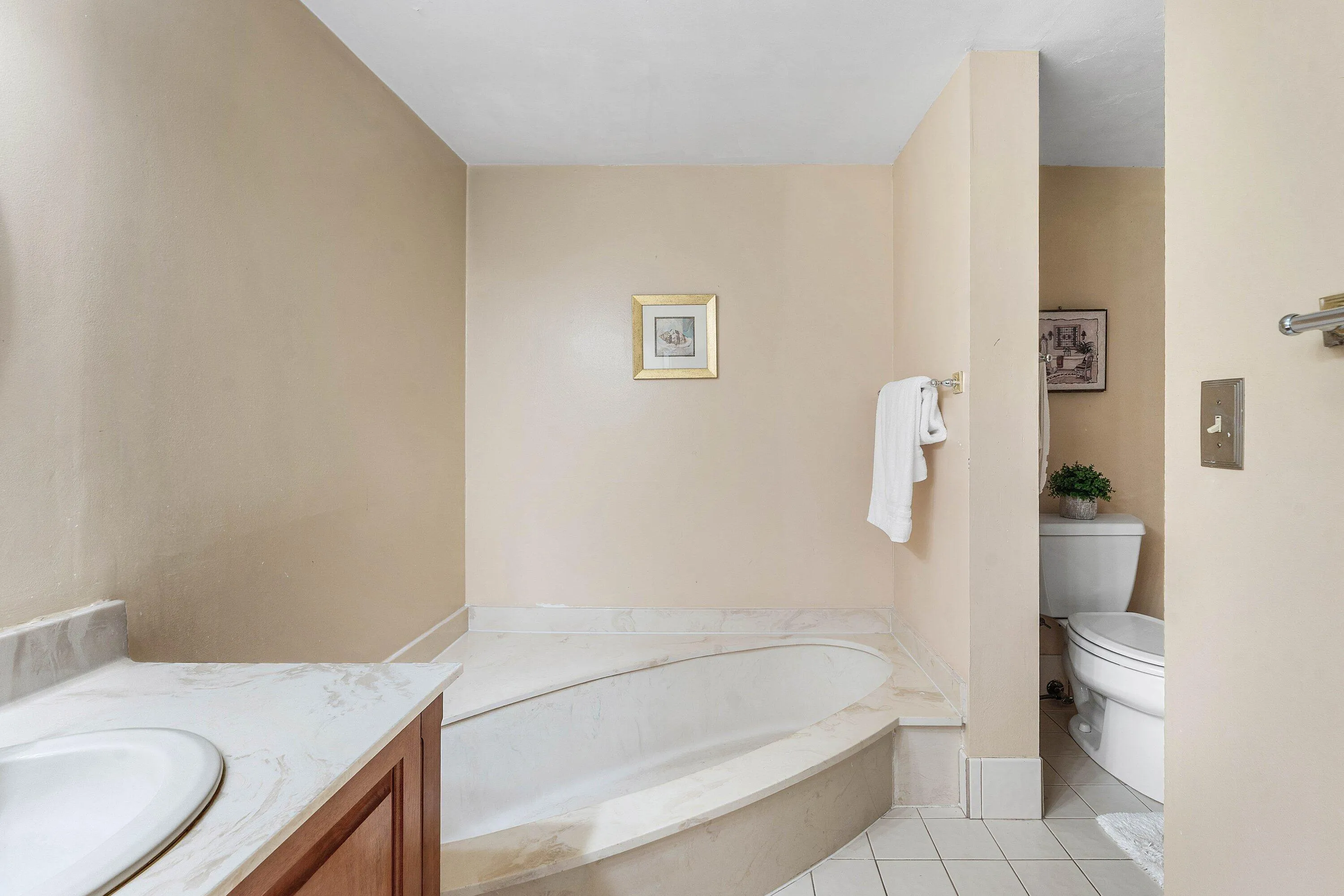 Built-in soaking tub with a stone surround, complemented by a vanity with an undermount sink and stone countertop