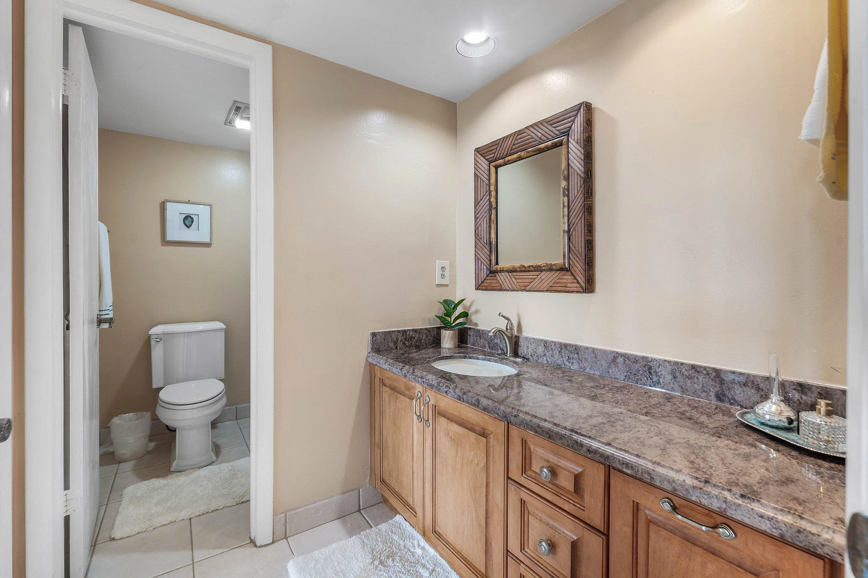 Vanity with a polished stone countertop and integrated basin sink, complemented by wood-finish cabinetry
