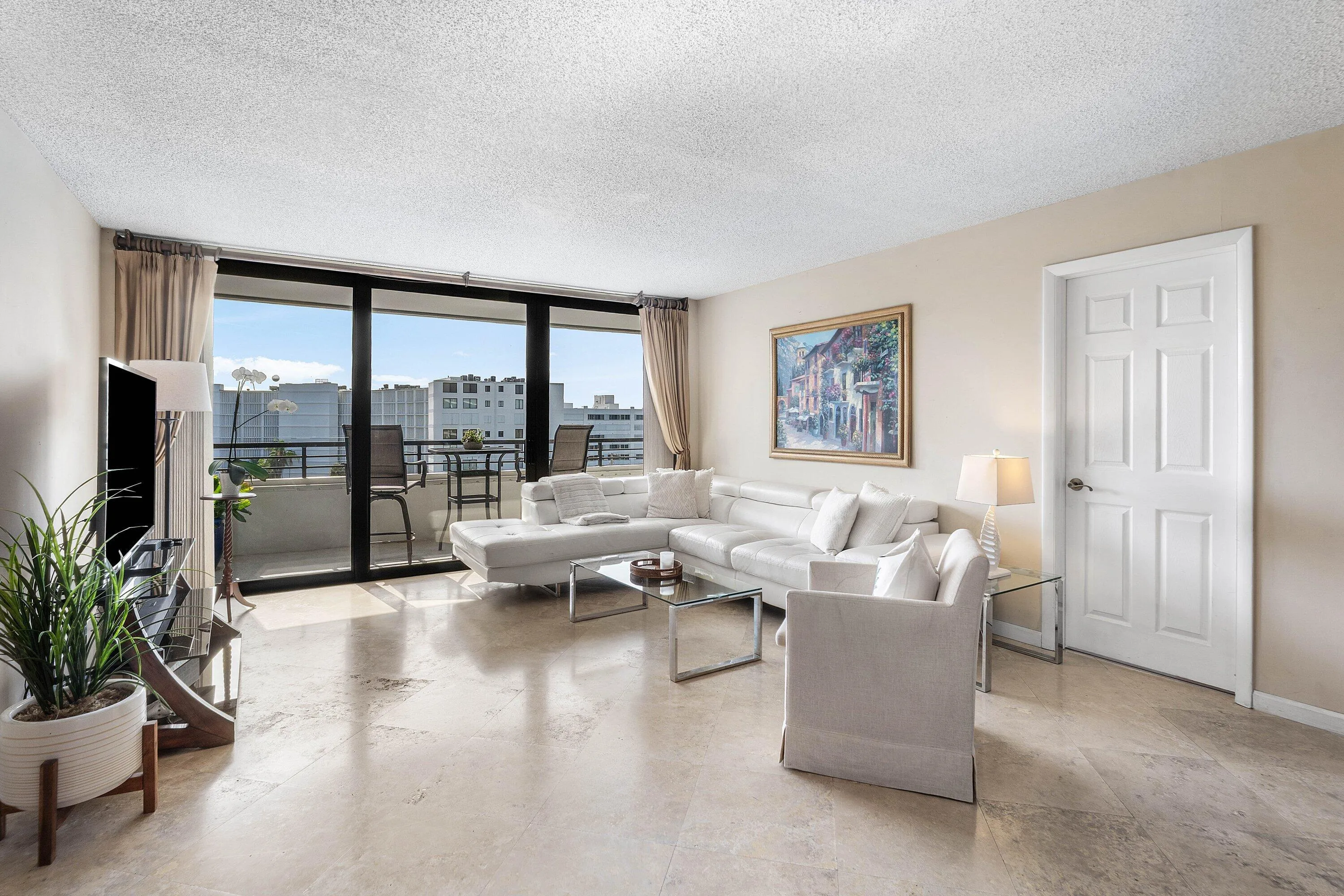 Spacious living area featuring full-height sliding impact glass doors opening to a private balcony
