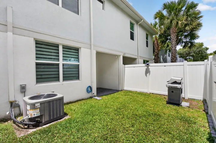 Private fenced yard featuring a manicured lawn, white vinyl fencing, and a covered patio area