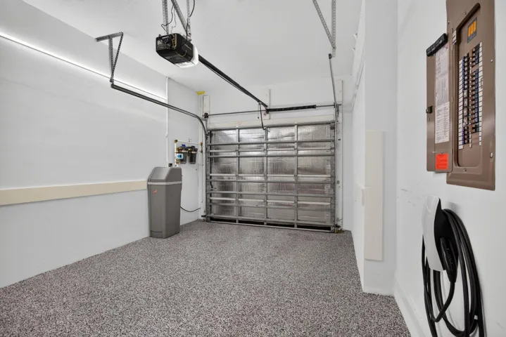 Garage interior featuring a speckled epoxy floor, an insulated garage door, an automatic opener, a water filtration system, and an EV charging station