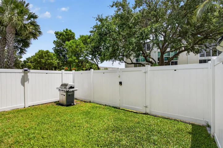 Private outdoor space featuring a lush green lawn and white privacy fencing
