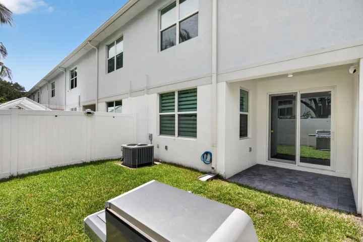 Backyard featuring a privacy fence, manicured lawn, and a paved patio area