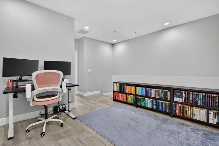 Spacious loft featuring light gray walls, wood-finish flooring, and recessed lighting