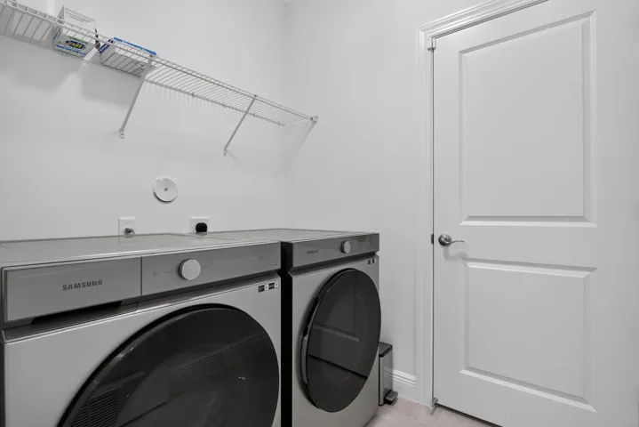 Laundry area with wire shelving, light-toned walls, and a paneled door with brushed nickel hardware