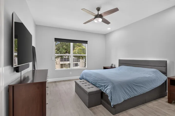 Spacious room with light gray walls, wood-finish flooring, and a ceiling fan with integrated lighting