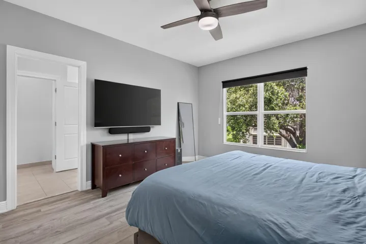 Spacious room featuring wood-finish flooring, a large window with exterior greenery, and a ceiling fan with integrated lighting