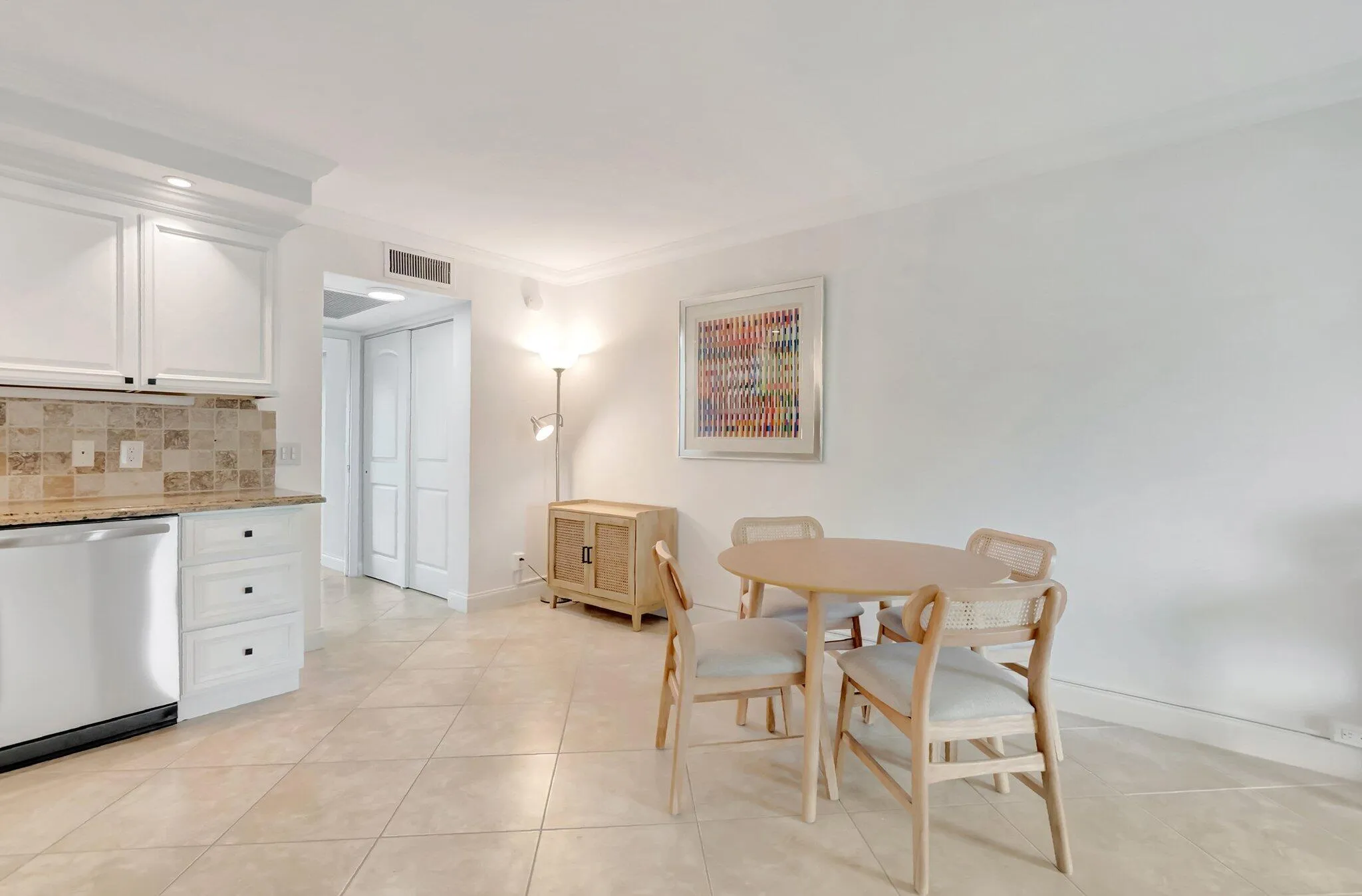 Kitchenette featuring white cabinetry, a stone-finish backsplash, and a built-in dishwasher