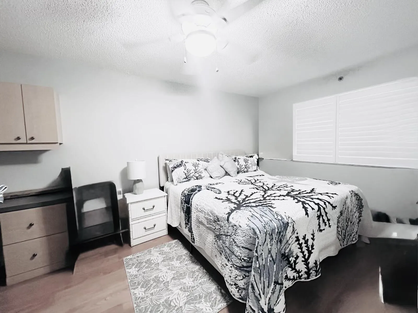 Bedroom featuring wood-finish flooring, a ceiling fan with integrated lighting, and plantation shutters