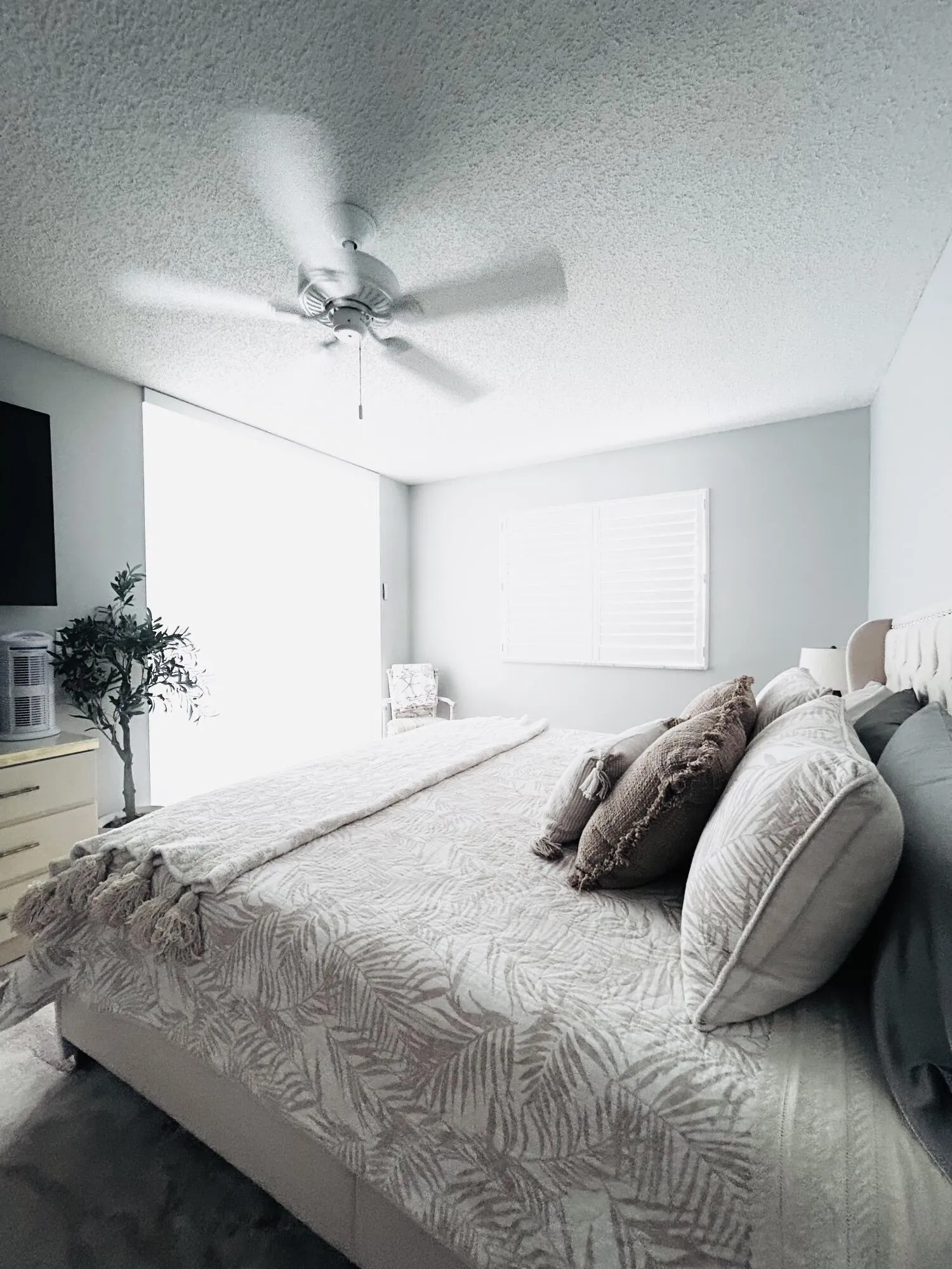 Spacious interior room featuring a ceiling fan, window with horizontal blinds, light-colored walls, and textured ceiling