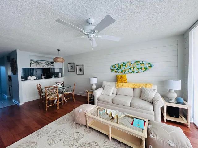 Open-concept living space with wood-finish flooring, a contemporary ceiling fan, and shiplap accent wall