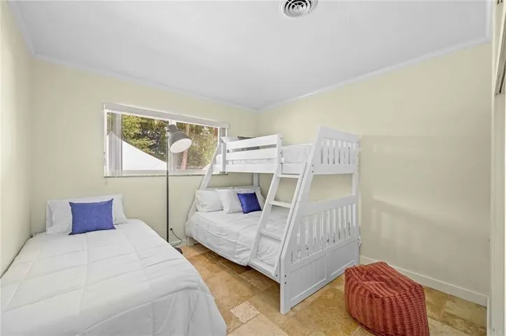 Bedroom featuring light-toned walls, white crown molding, and a recessed ceiling vent
