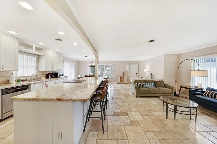 Spacious kitchen featuring an elongated island with integrated seating, white cabinetry, and granite countertops