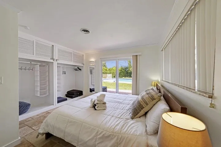 Room featuring stone-finish tile flooring, built-in open shelving with upper louvered cabinetry, and sliding glass doors with direct outdoor access