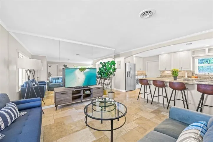 Open-concept living space featuring expansive mirrored walls, light-toned tile flooring, and recessed lighting