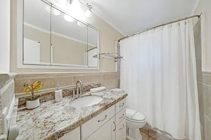 Bathroom vanity featuring a granite countertop, undermount sink, and brushed nickel faucet