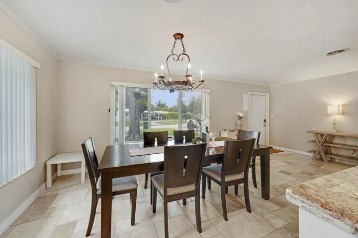 Spacious dining area featuring neutral wall tones, tile flooring, and a decorative chandelier