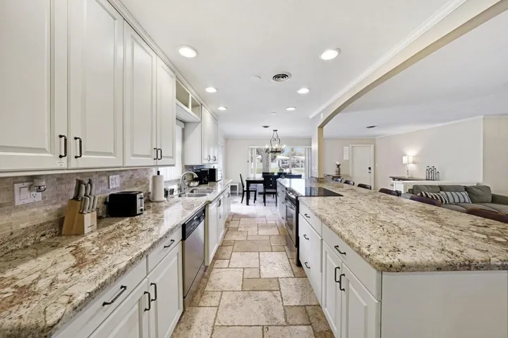 Kitchen featuring extensive light-toned cabinetry with dark hardware, stone countertops, and tile flooring
