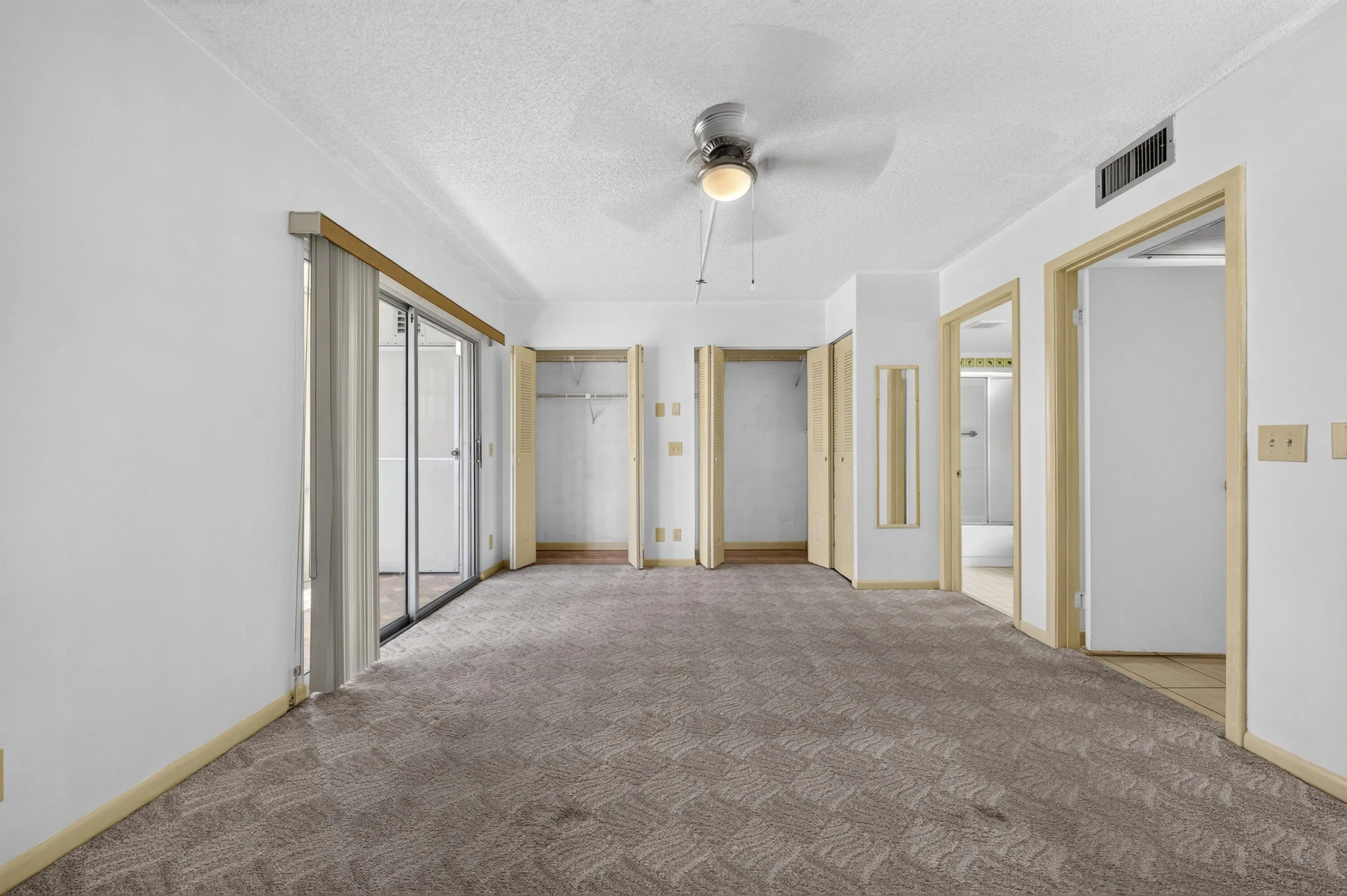 Spacious room featuring patterned carpeting and white painted walls