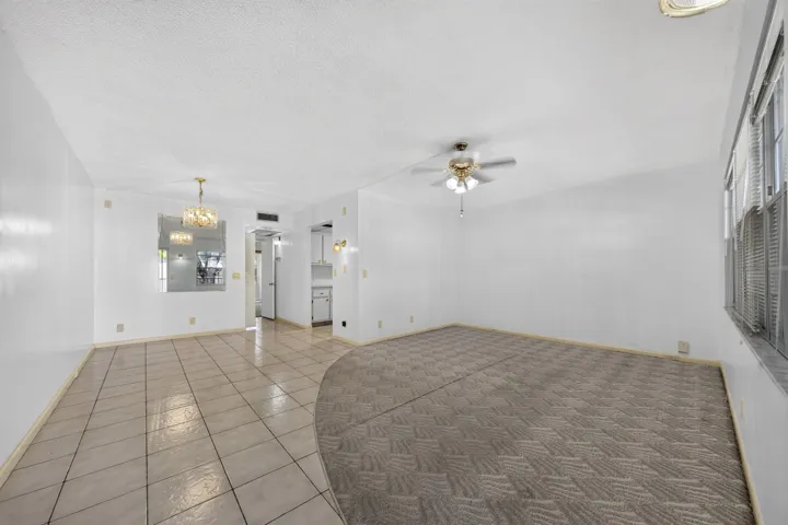 Spacious living area featuring a combination of patterned carpet and diagonal tile flooring