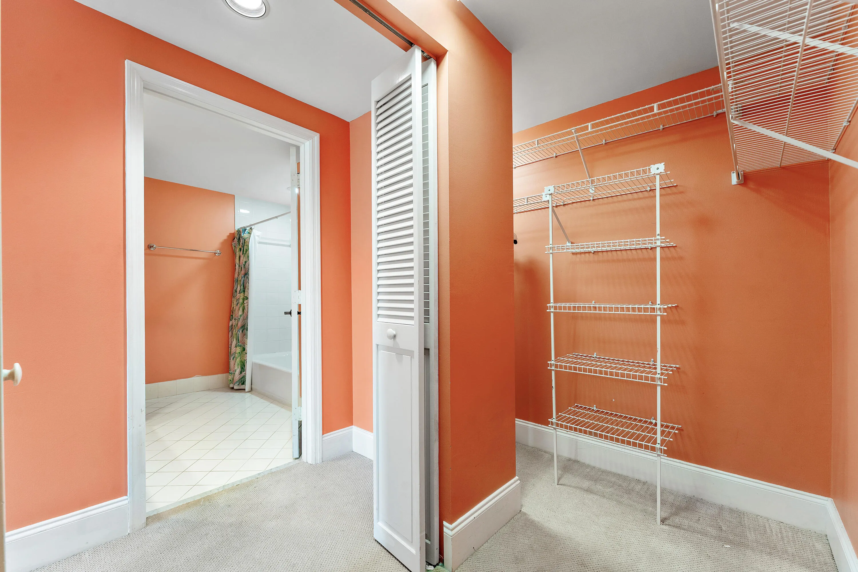 Integrated closet system featuring wire shelving, wire hanging rods, and an accordion-style bi-fold door