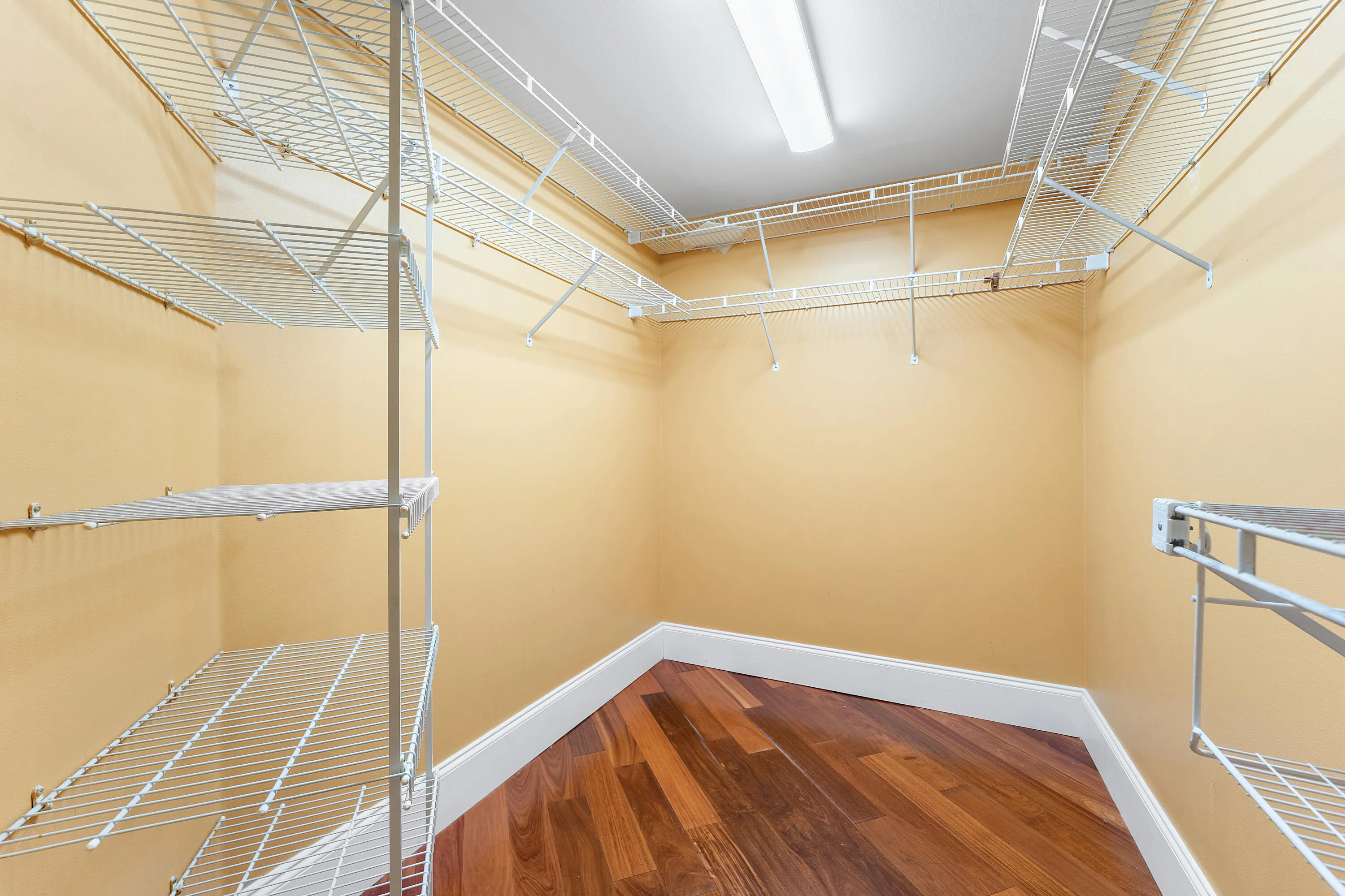 Walk-in closet featuring wood-finish flooring, white wire shelving, a built-in hanging rod, and recessed ceiling lighting