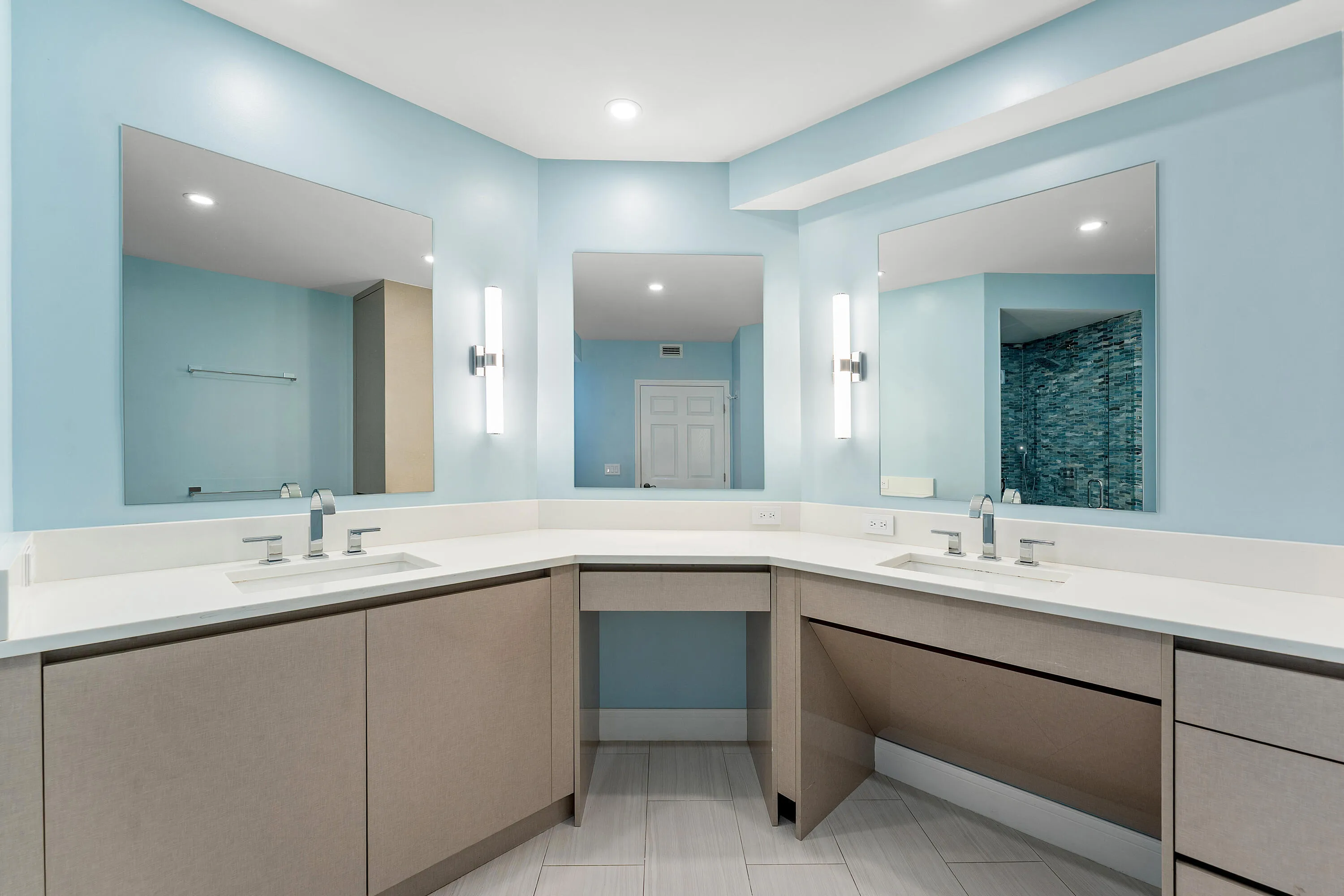 Dual vanity featuring integrated sinks, chrome fixtures, and sconce lighting