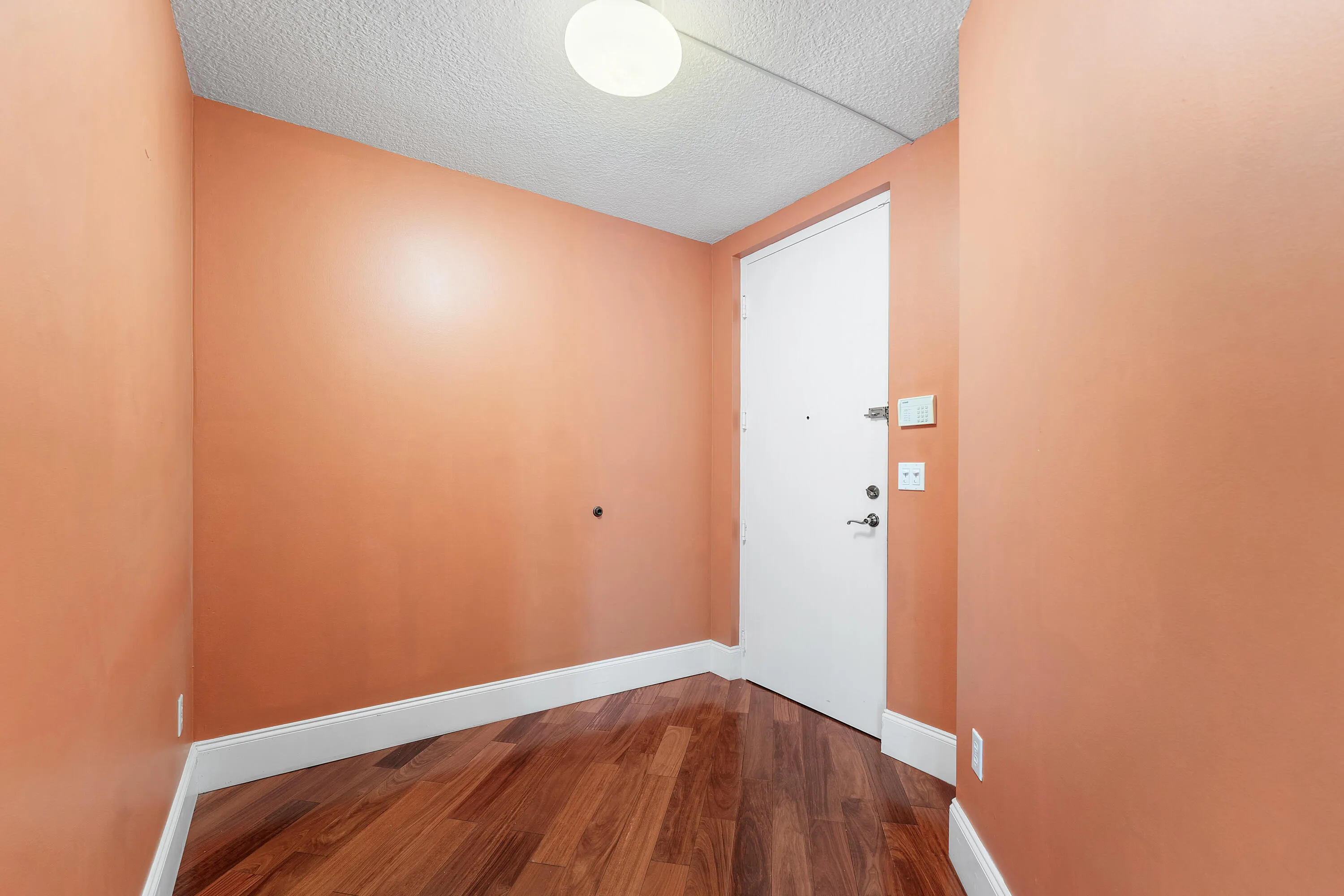 Entryway featuring wood-finish flooring, white baseboards, and a white entry door with chrome hardware