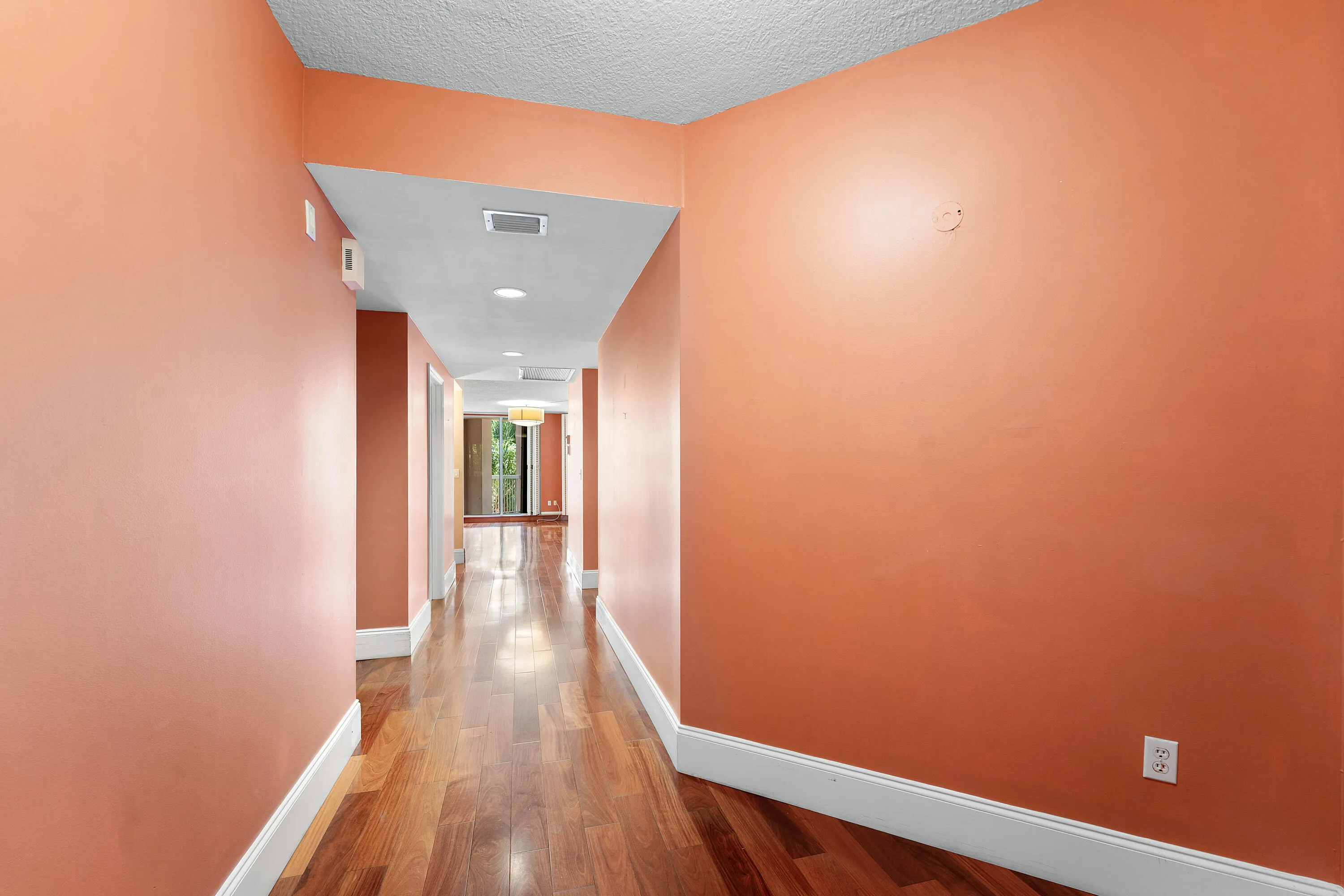 Long hallway featuring wood-finish flooring, recessed lighting, and a white baseboard trim