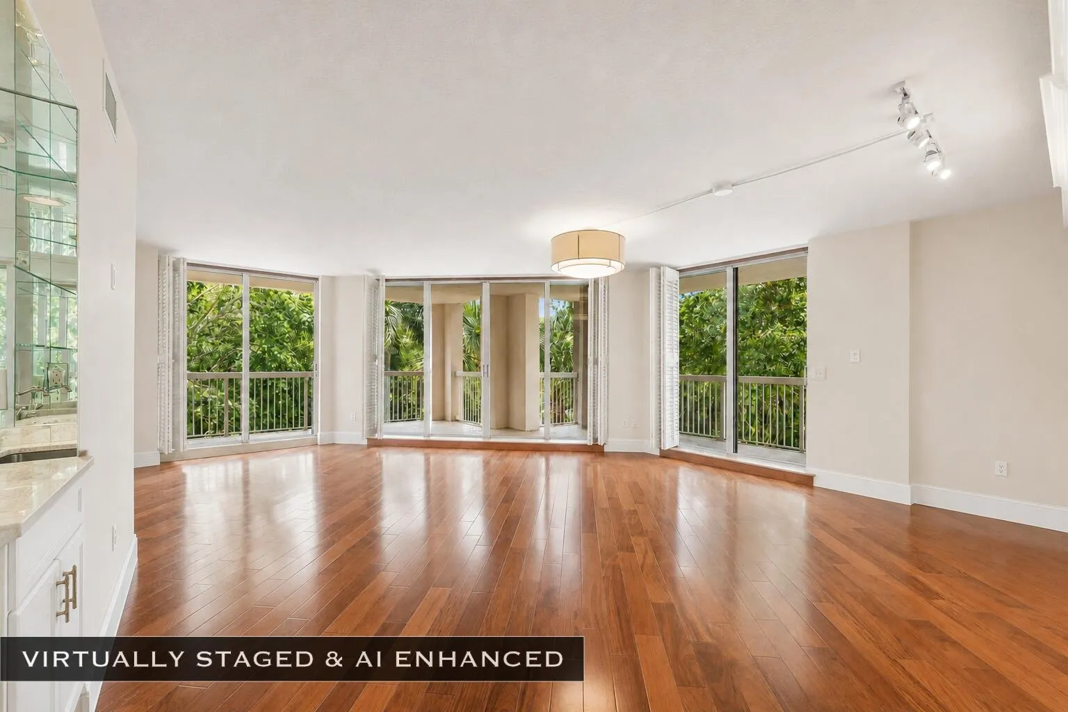 Spacious interior featuring wood-finish flooring, a built-in wet bar with glass shelving, multiple floor-to-ceiling glass doors, and a decorative ceiling light fixture
