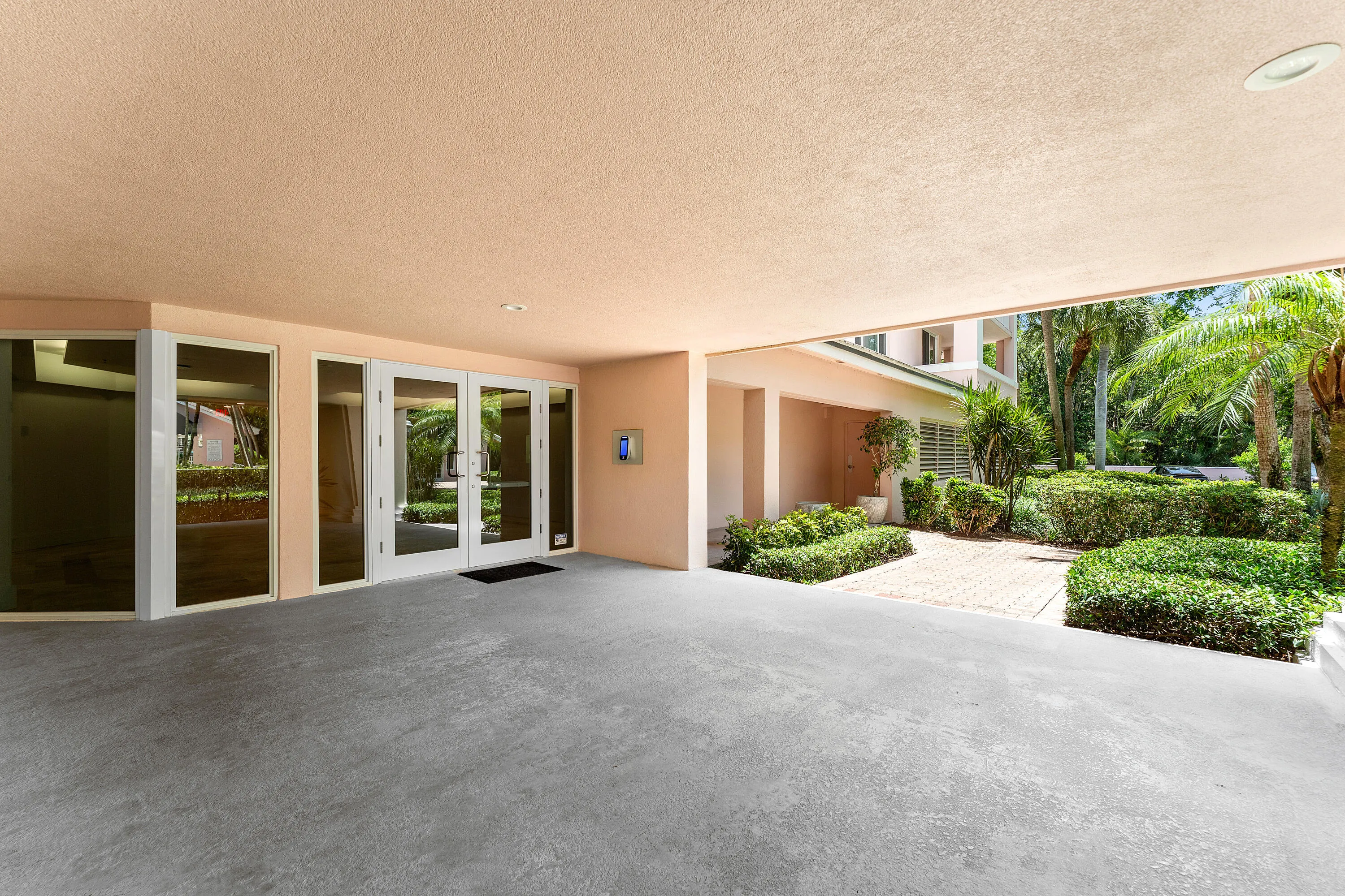 Covered entryway with triple glass panel doors, recessed lighting, and a textured concrete floor