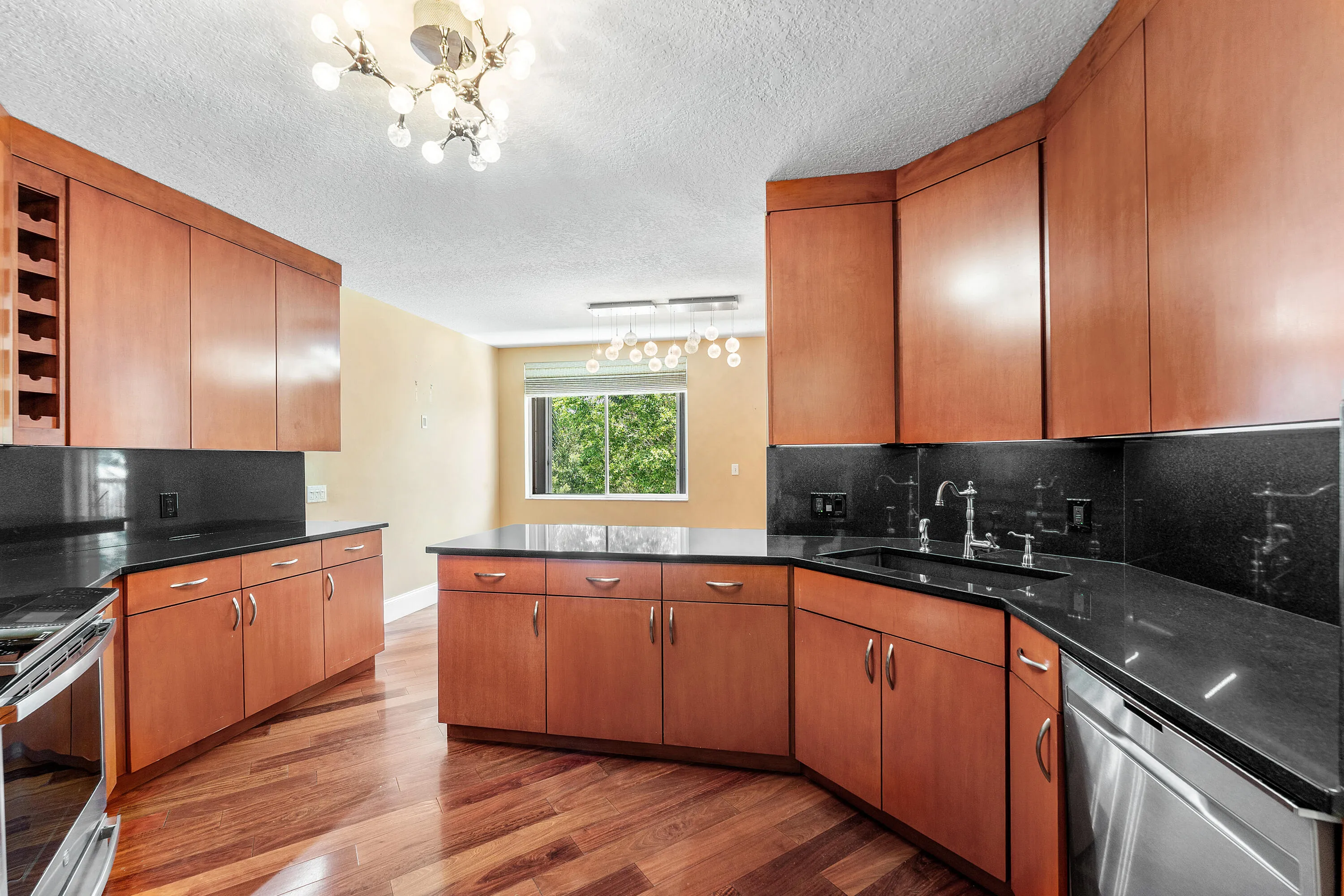 Kitchen featuring wood cabinetry, dark countertops, a built-in wine rack, stainless steel appliances, and wood-finish flooring